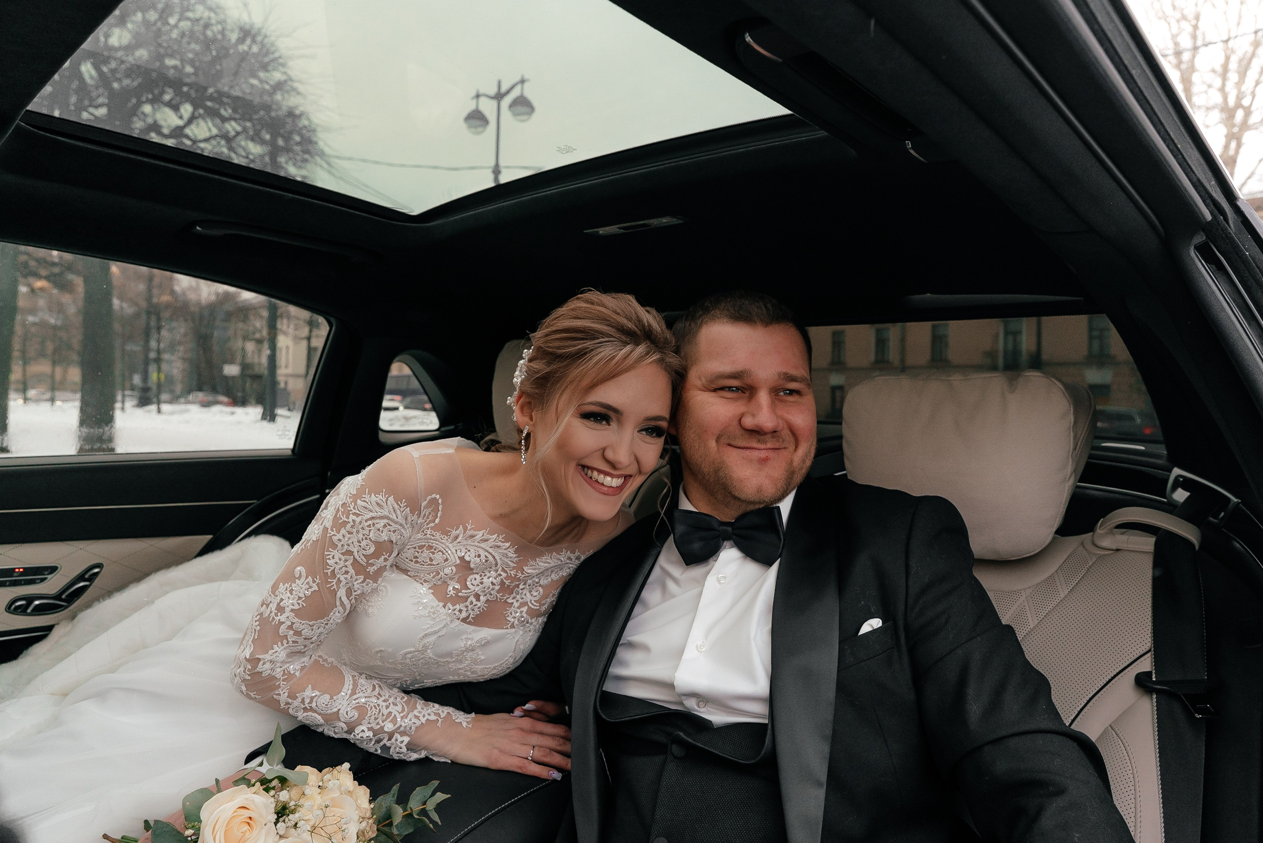 Свадебный портрет жениха и невесты в свадебном автомобиле зимой в Санкт-Петербурге