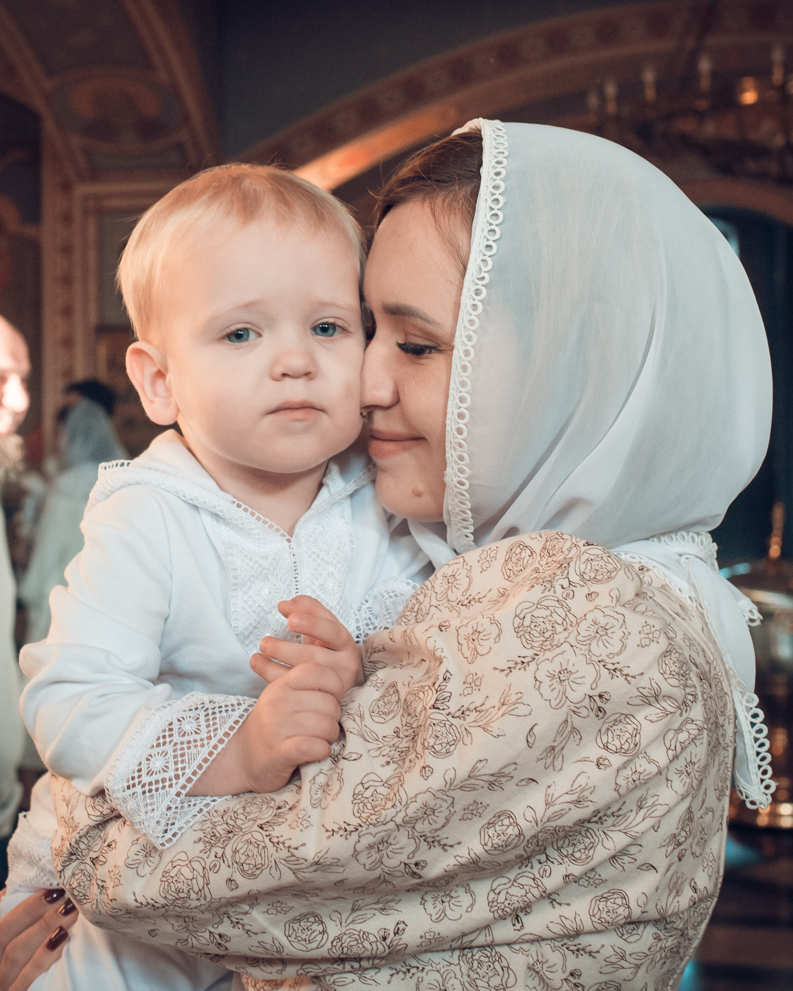 Мама с ребенком на руках во время таинства Крещения в храме, фотограф Василий Дан