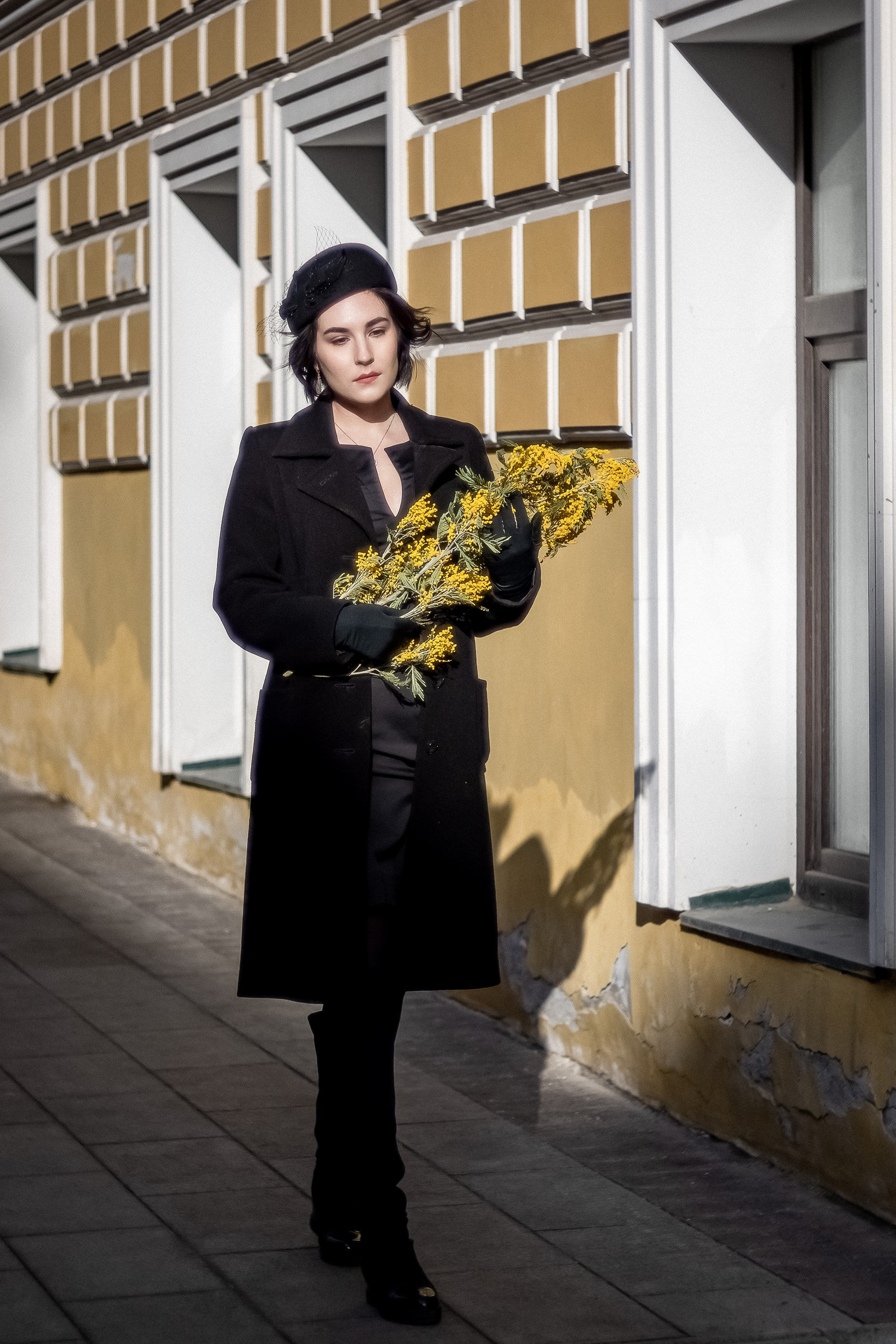 девушка в пальто в руках букет мимозы