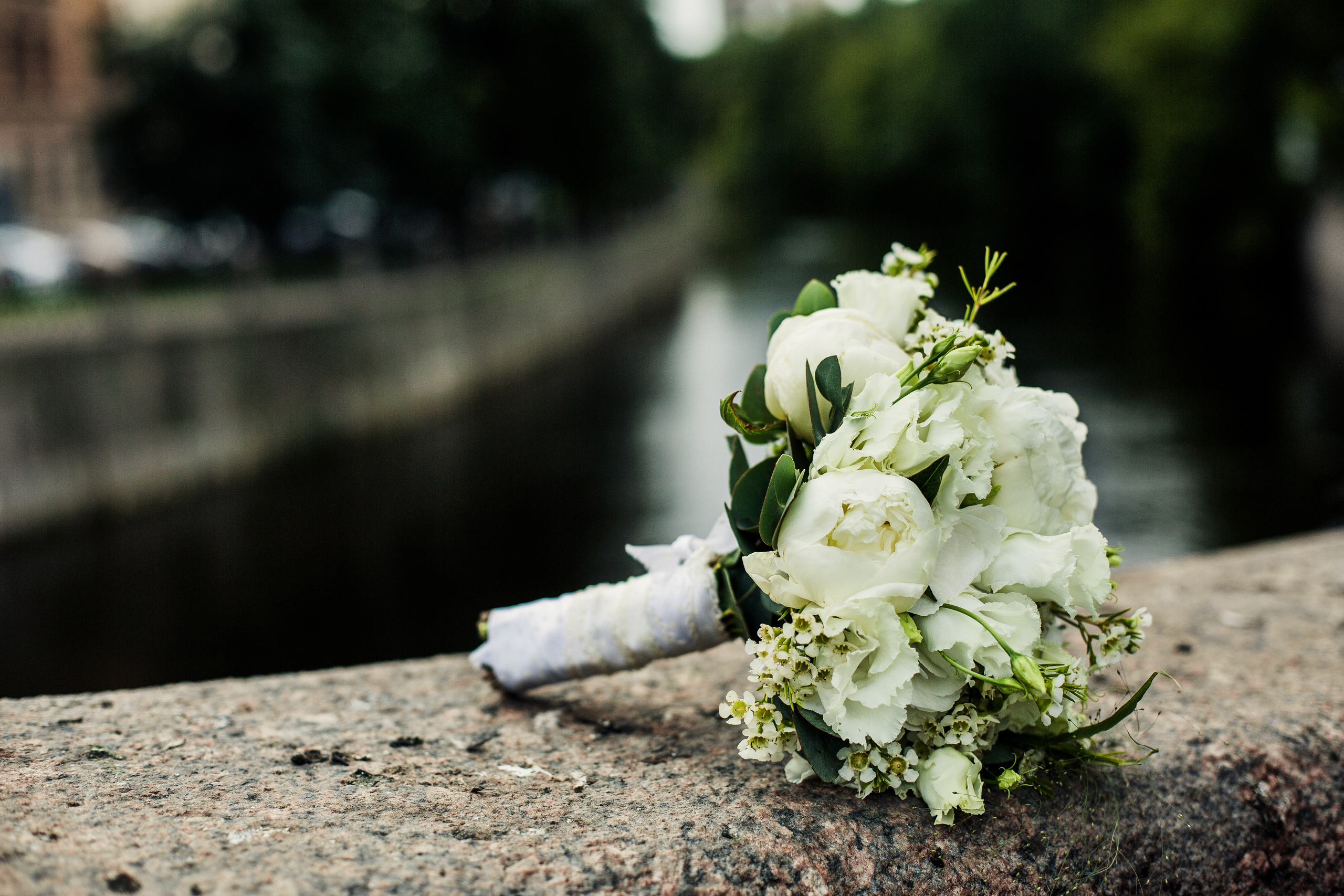 белый свадебный букет на бортике гранитной набережной у изгиба реки