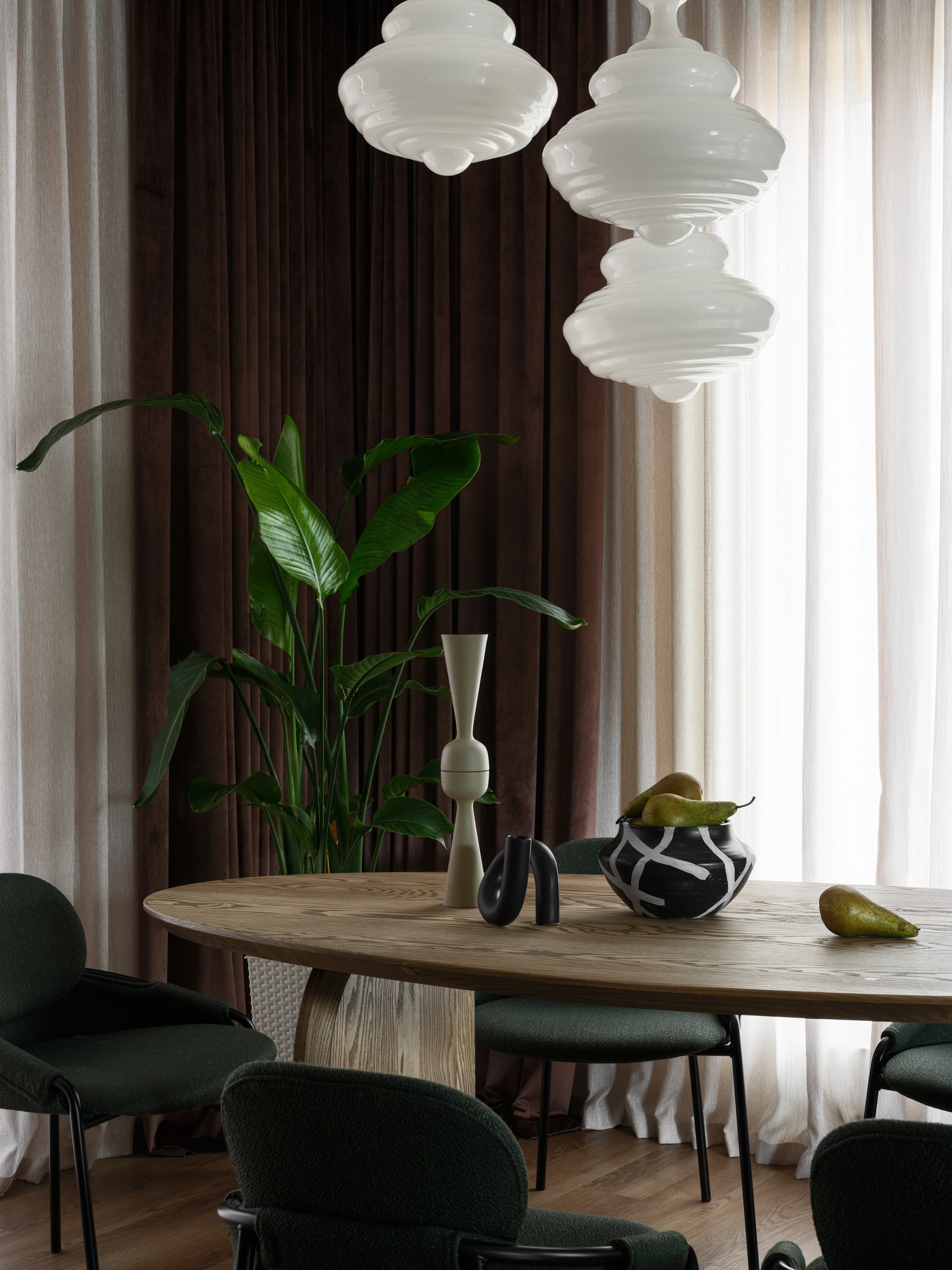 Столовая с круглым деревянным столом и стильными зелёными креслами, дополненная белыми подвесными светильниками и декоративными акцентами. Интерьер Наталии Шелепниковой, фото Сергея Денисенко, стилизация Алёны Бершацкой.