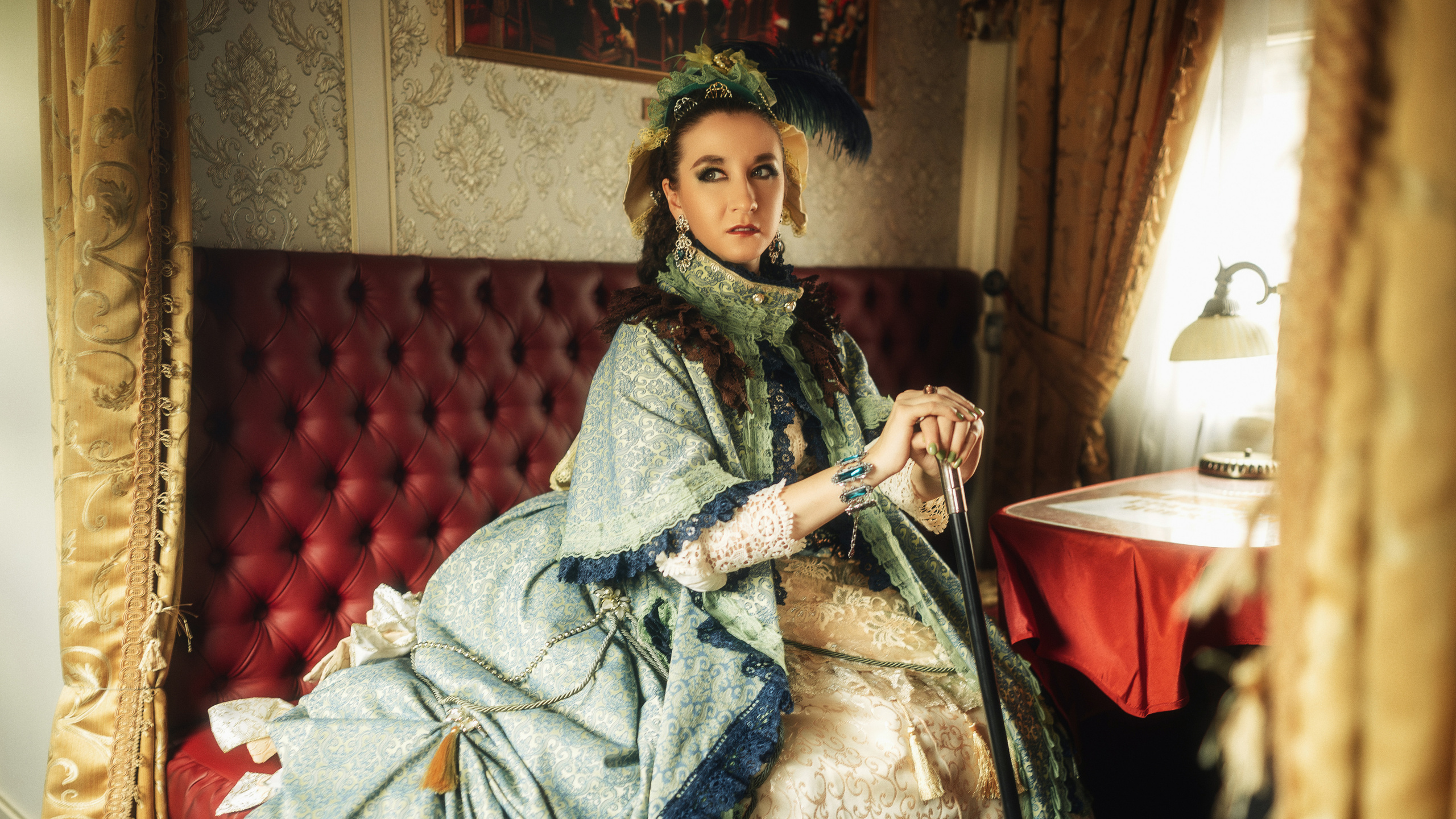 Девушка в шикарном, историческом платье в поезде сидит на кресле.