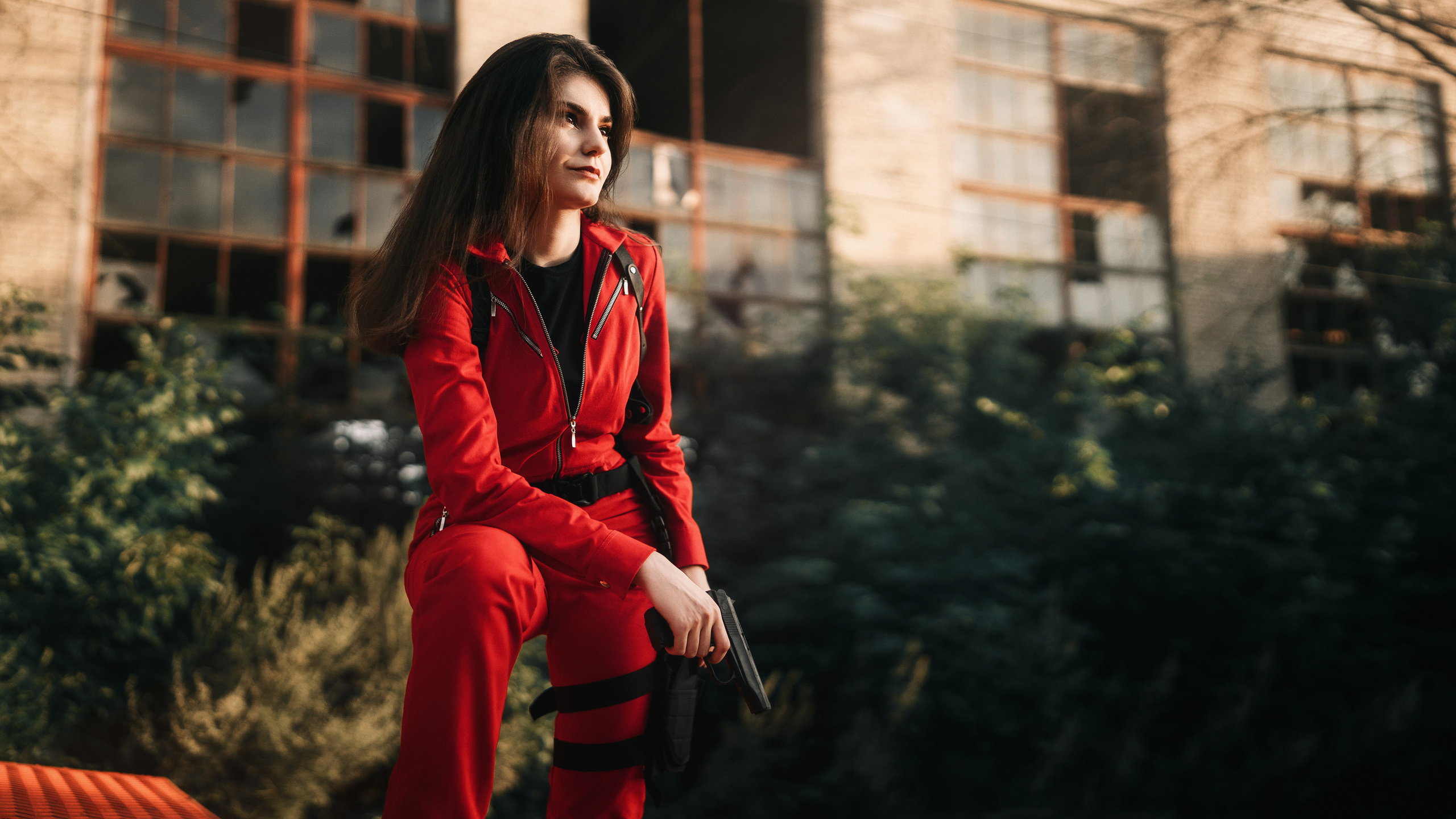 Девушка в красном комбинезоне смотрит в даль.