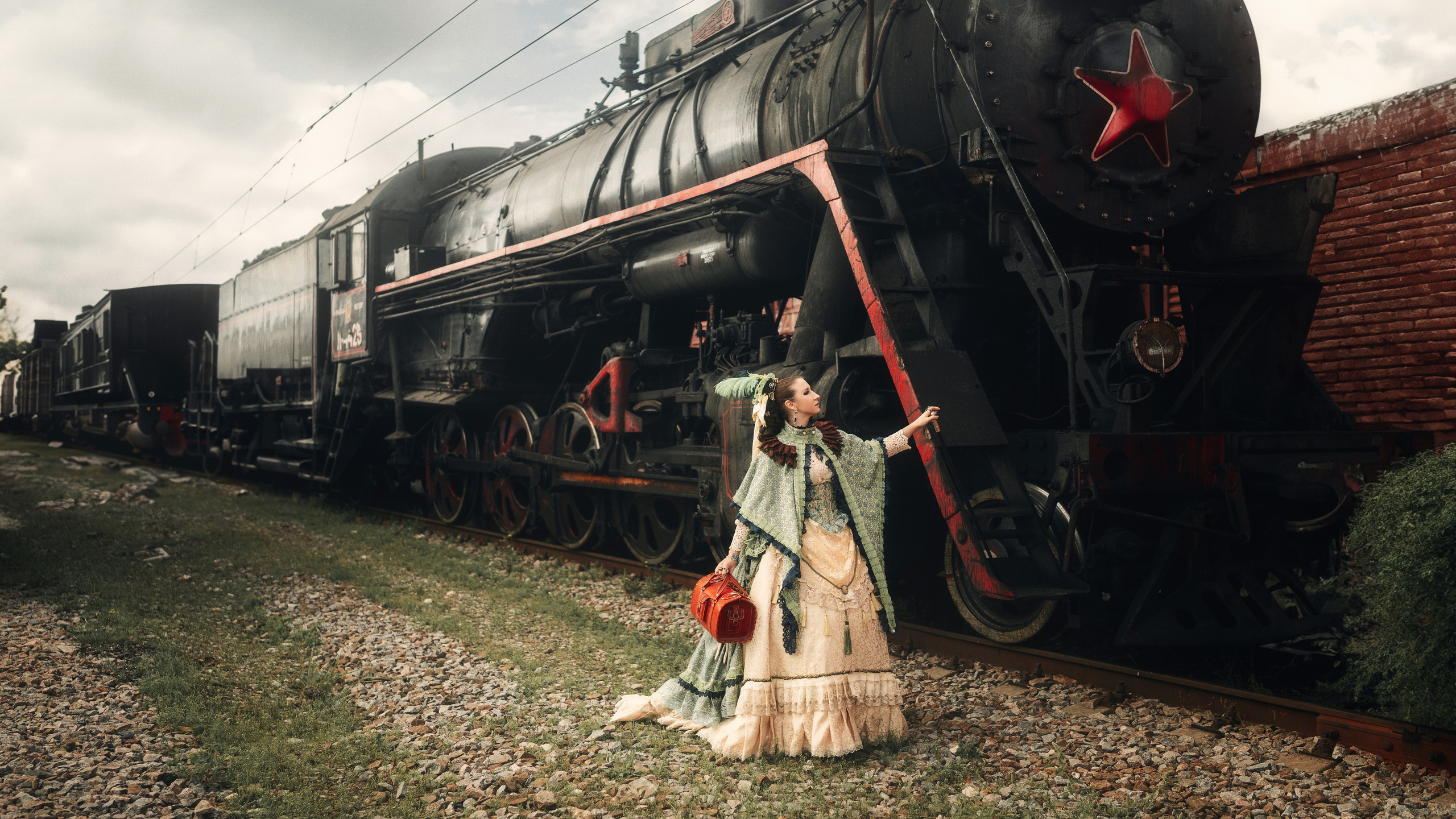 Девушка в шикарном, историческом платье стоит у поезда.