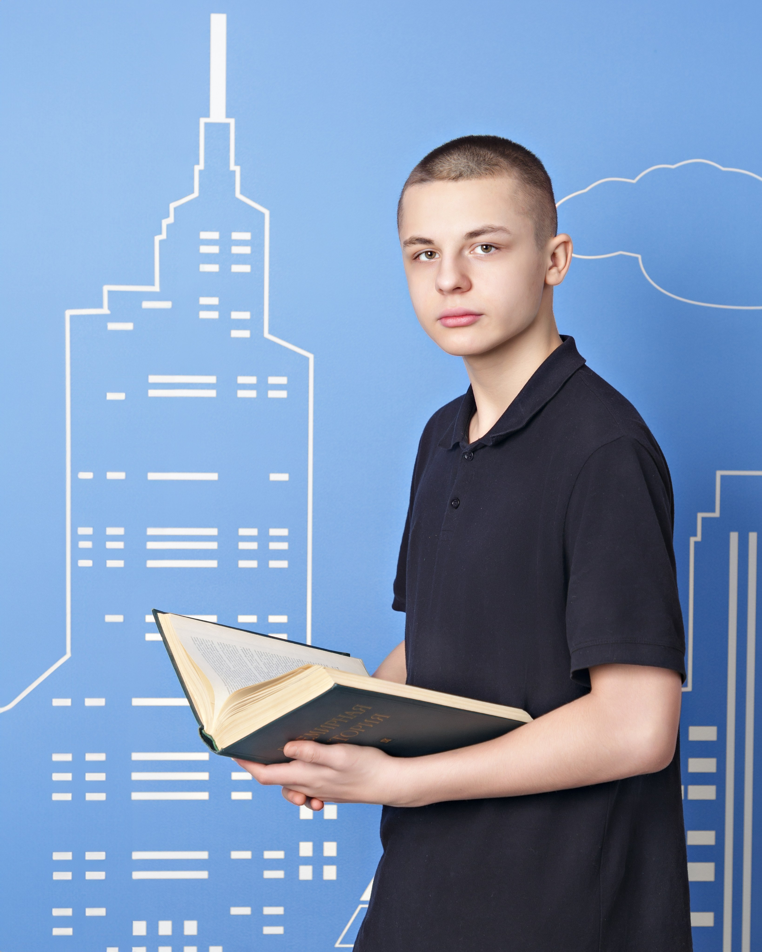 Мальчик держит книгу, позирует на синем фоне с городской графикой.