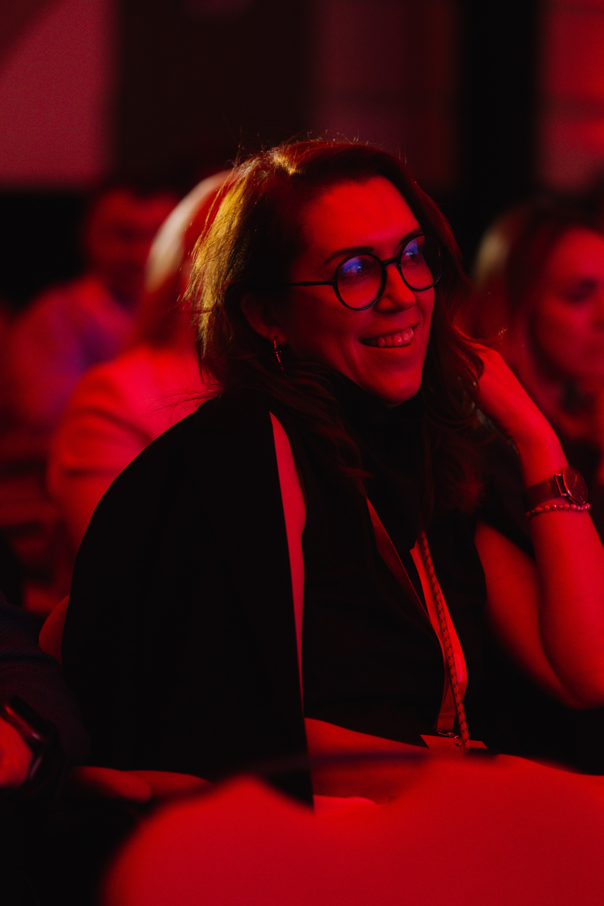 Эмоции: Крупный план смеющейся гостьи в зале, передающий позитивную атмосферу бизнес-форума.