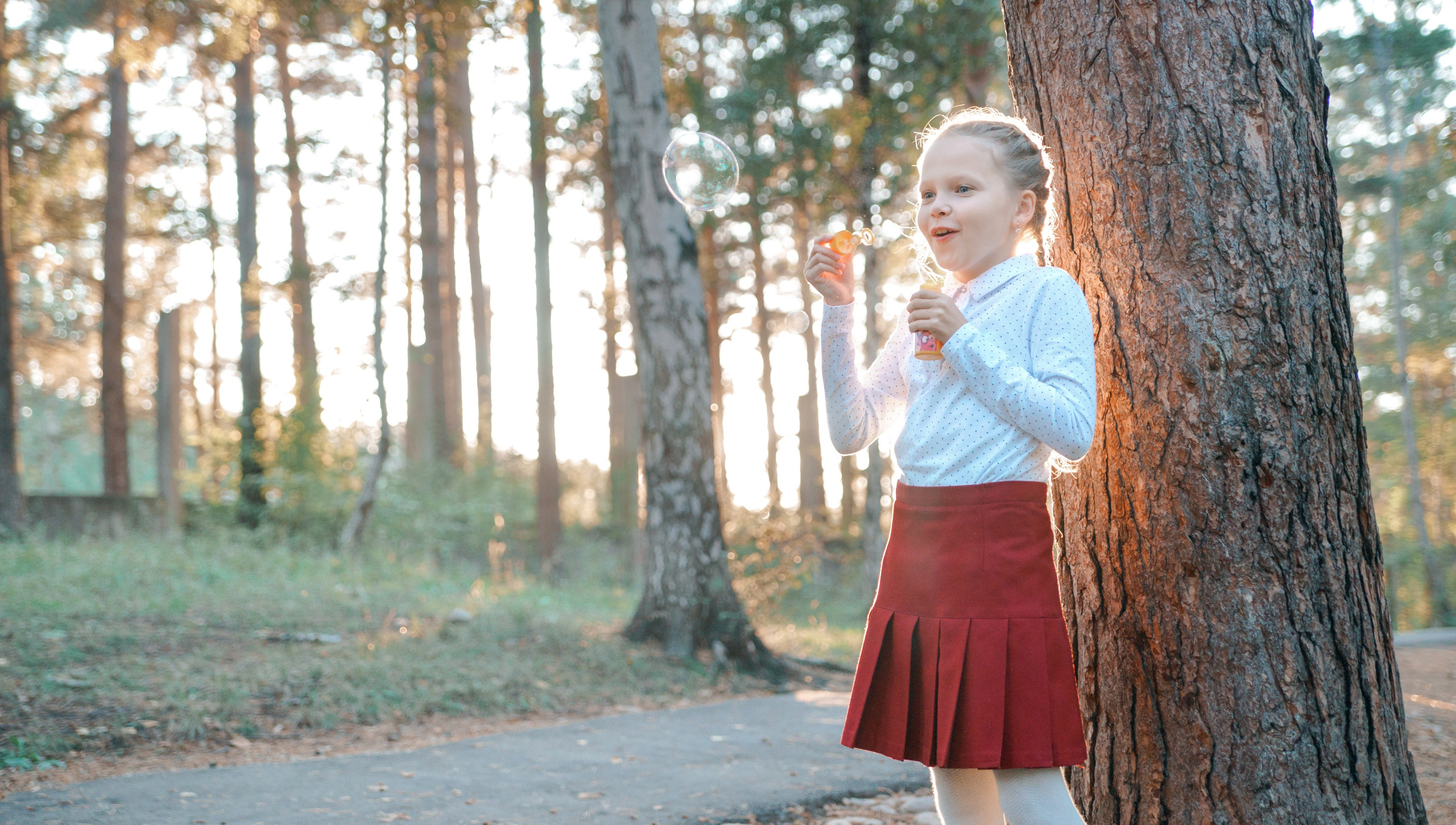 Детская фотосессия осенью - школьница стоя дует мыльные пузыри