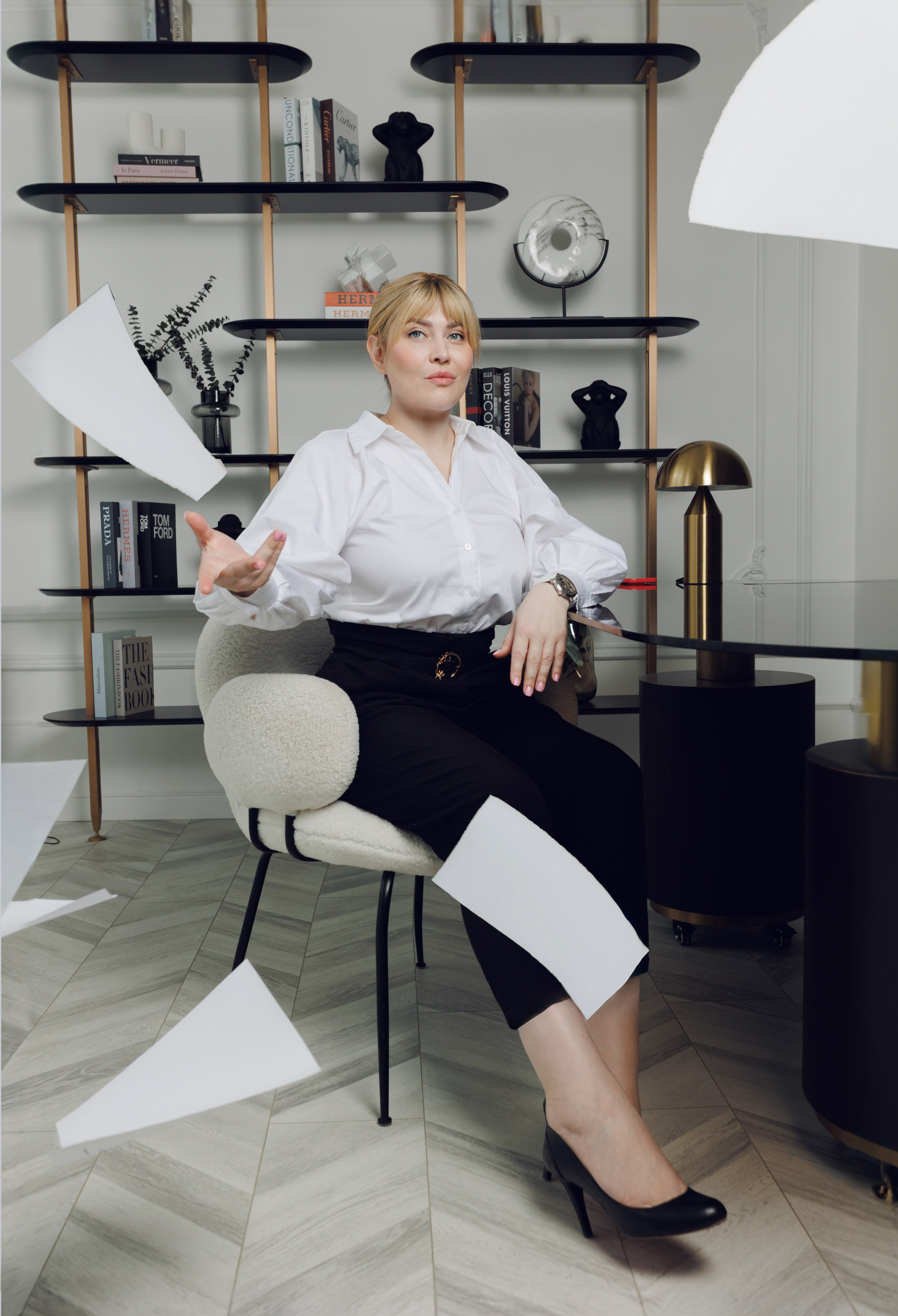 Динамичный кадр: девушка в офисе сидит на стуле и разбрасывает документы.