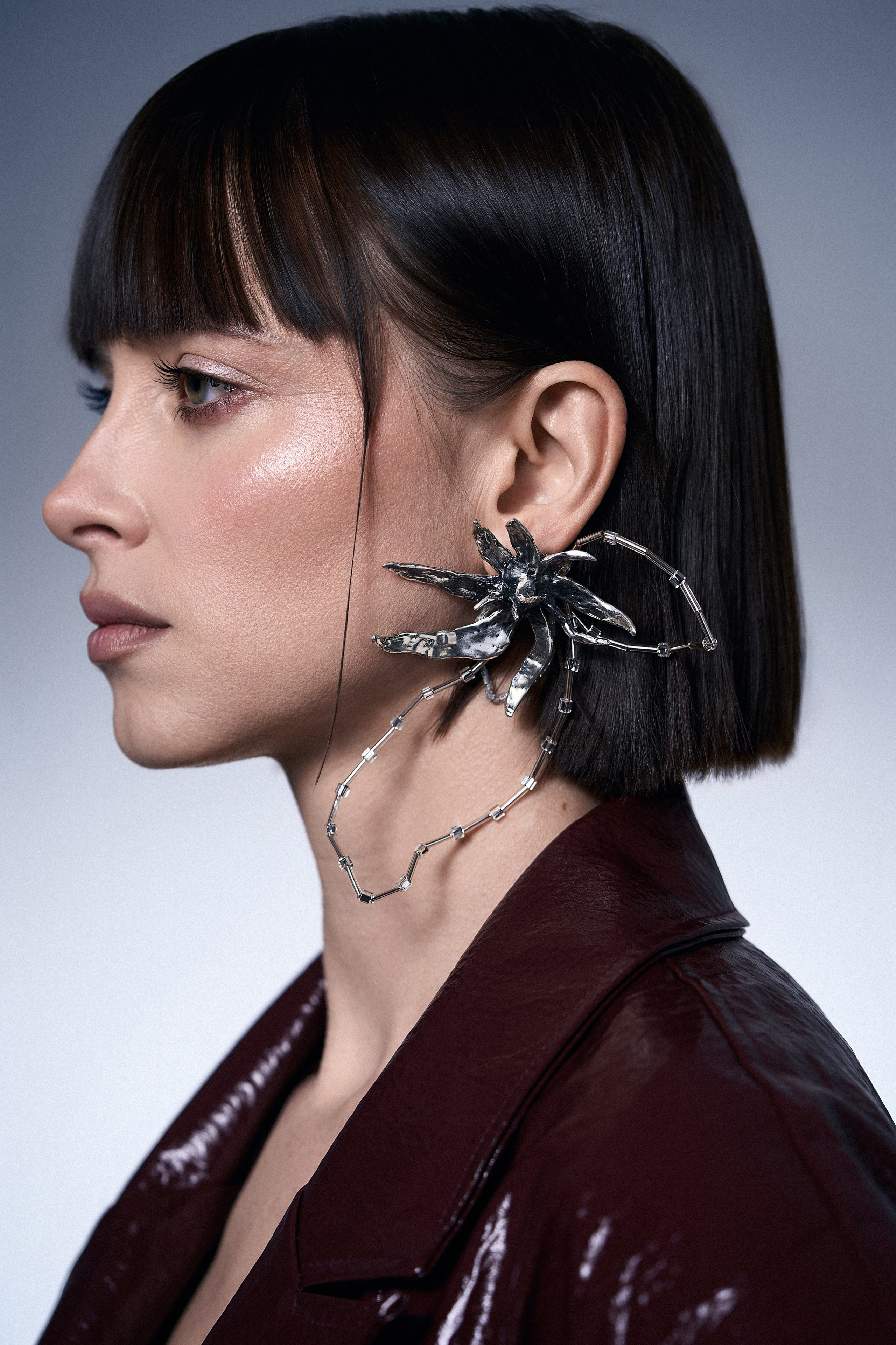 Профиль модели с крупной асимметричной серьгой Sergacheva Jewelry и бордовым жакетом