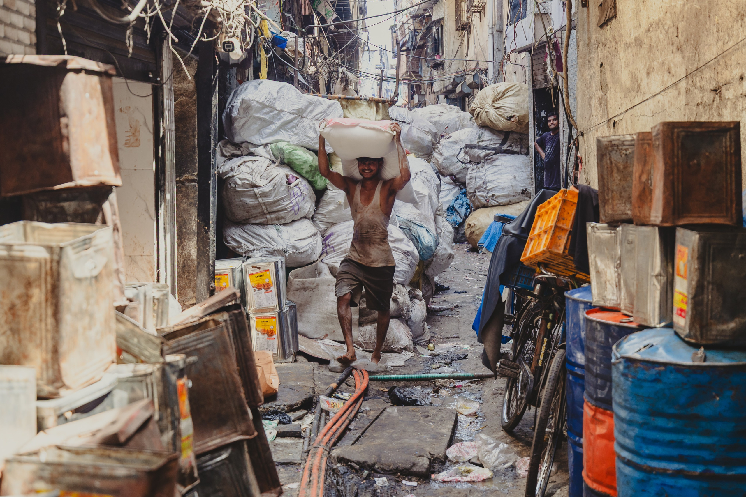 Люди в узком переулке бедного района среди больших мешков