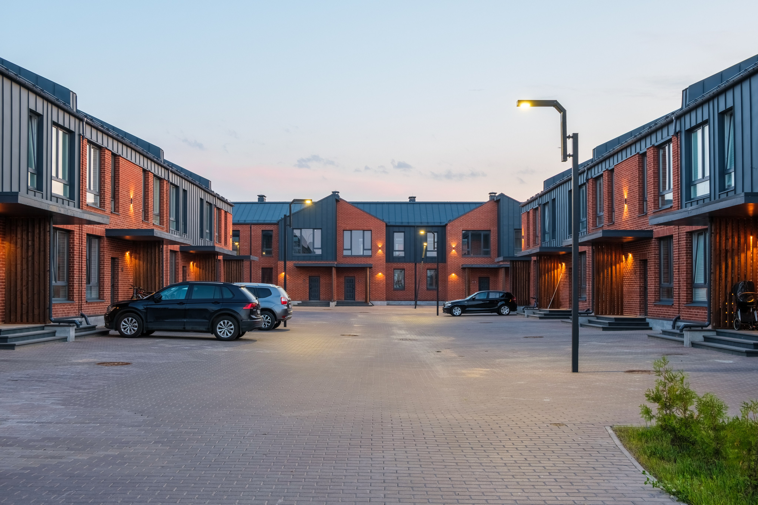 Двор современного коттеджного посёлка с парковочными местами. Включено уличное освещение.