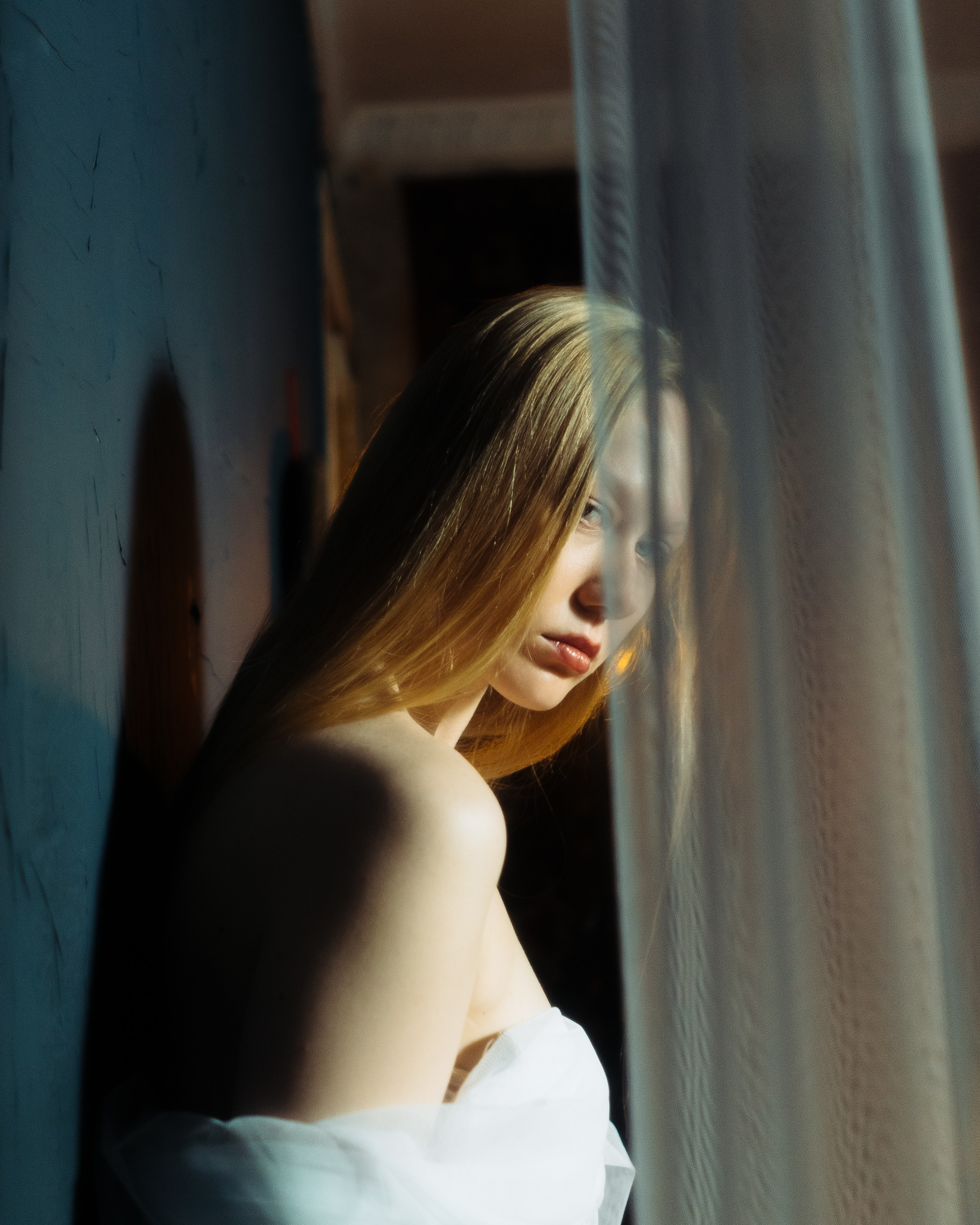 Крупный женский портрет у окна и легкой ткани, авторская фотосессия девушки в студии с мягким пленочным светом
