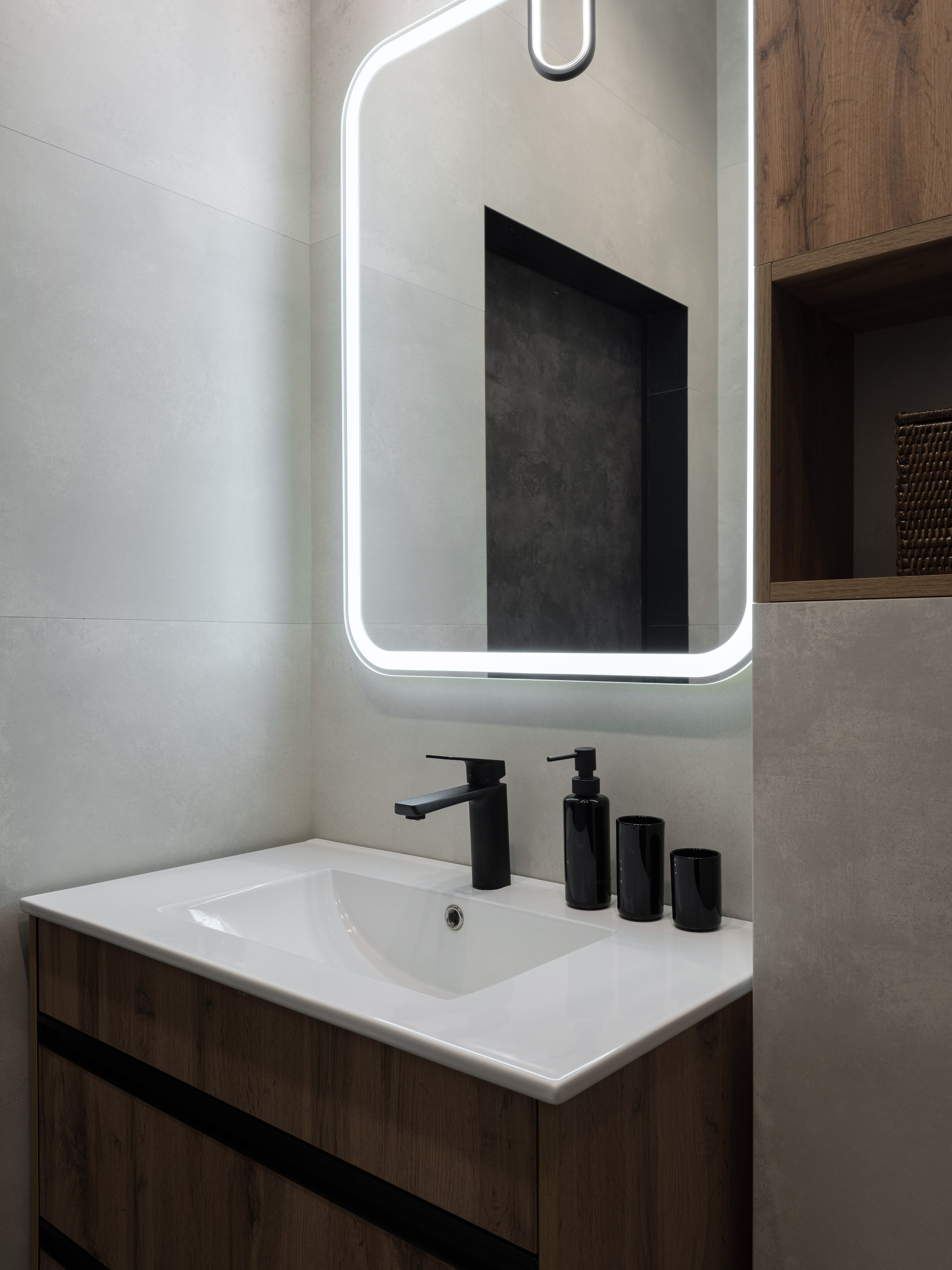 Интерьер ванной комнаты с подсвеченным зеркалом, чёрным смесителем и мебелью под дерево. Дизайн, сочетающий практичность и эстетику, создан дизайнером Алиной Дёровой, стилистом Натальей Якушевой, сфотографирован Сергеем Денисенко.