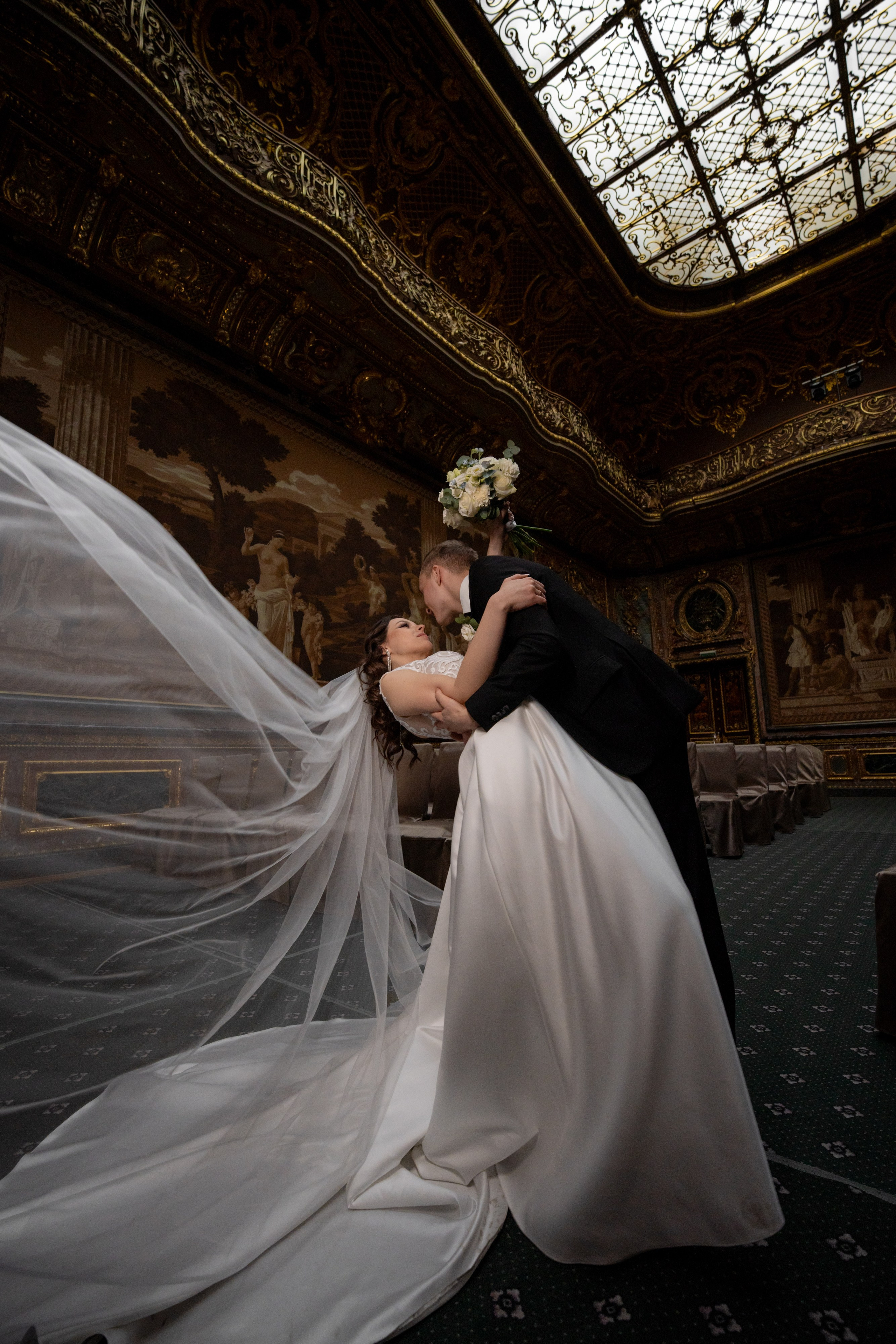Свадебная фотосессия в Санкт-Петербурге в Особняке Половцева или Дом Архитектора. Жених красиво целует невесту с прогибом и фата летит в зале театра в полный рост.