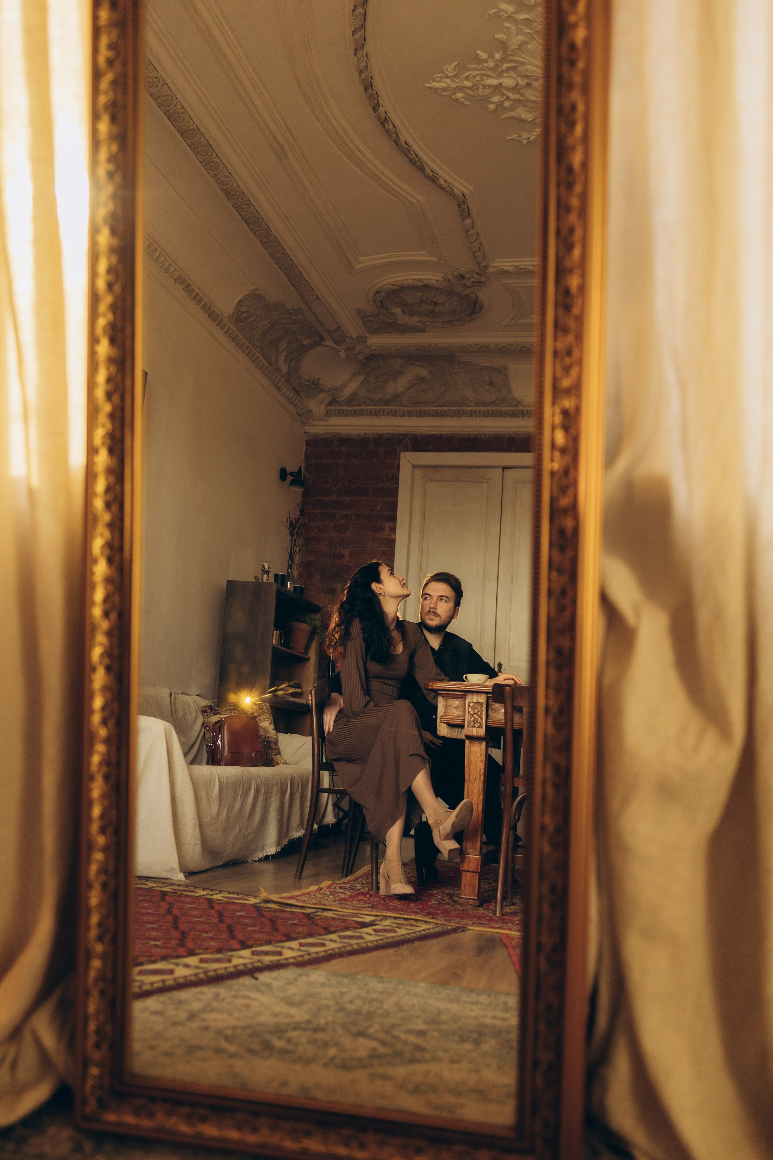 Невеста и жених сидят рядом, скрестив ноги, держась за руки