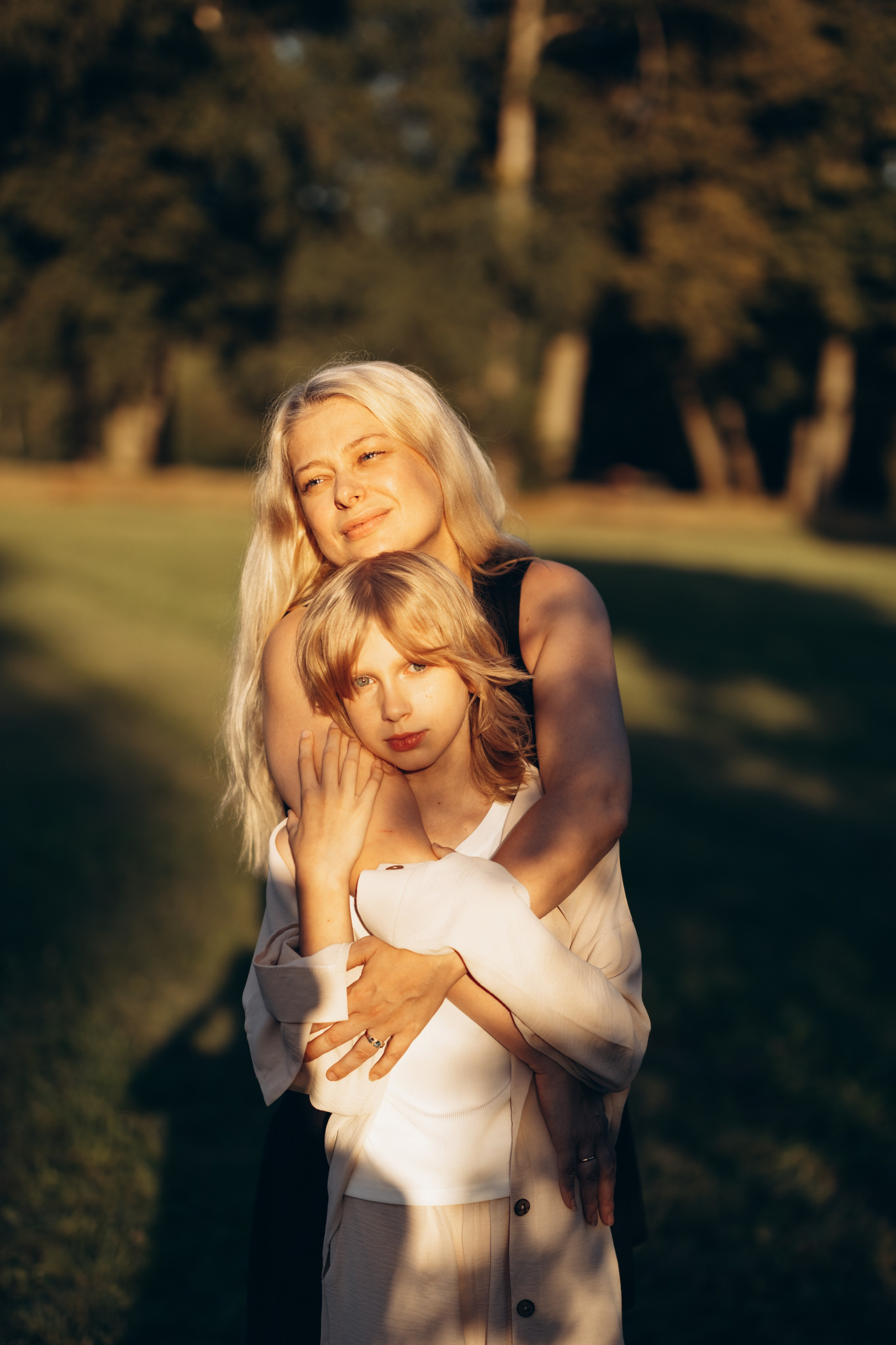 Родители обнимают ребенка на семейной фотосессии в парке