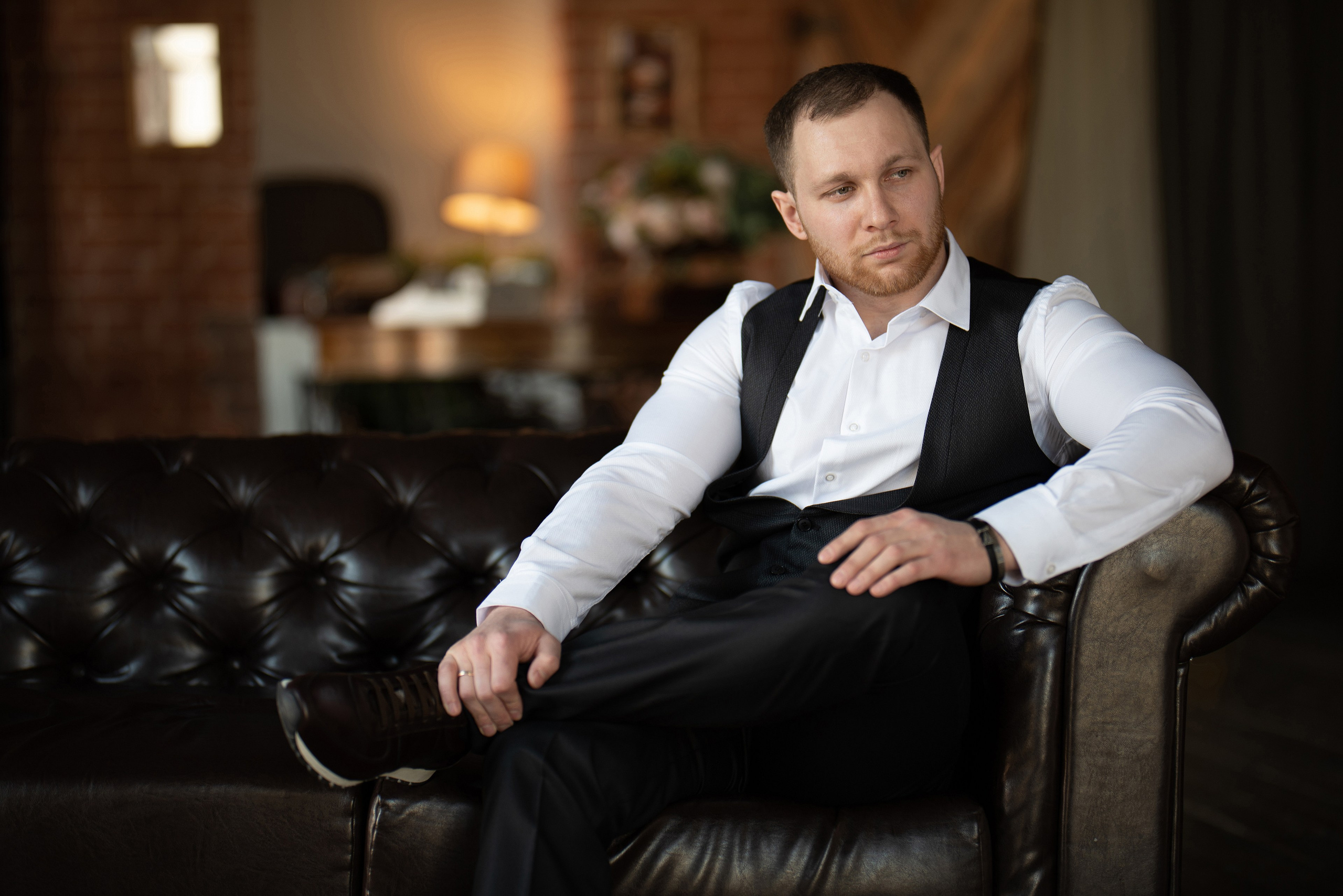 Мужчина сидит на кожаном диване в фотостудии.