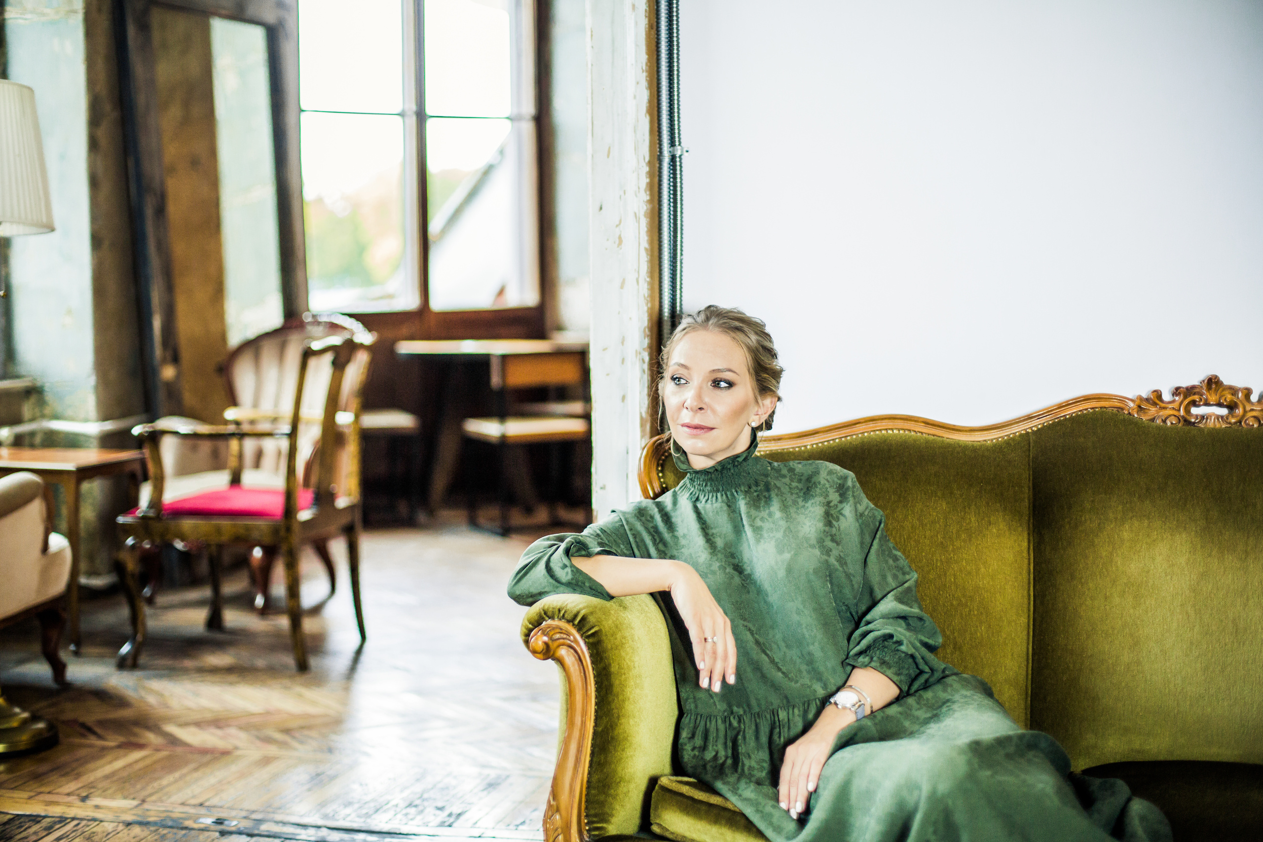 женщина в изумрудном платье на зеленой кушетке