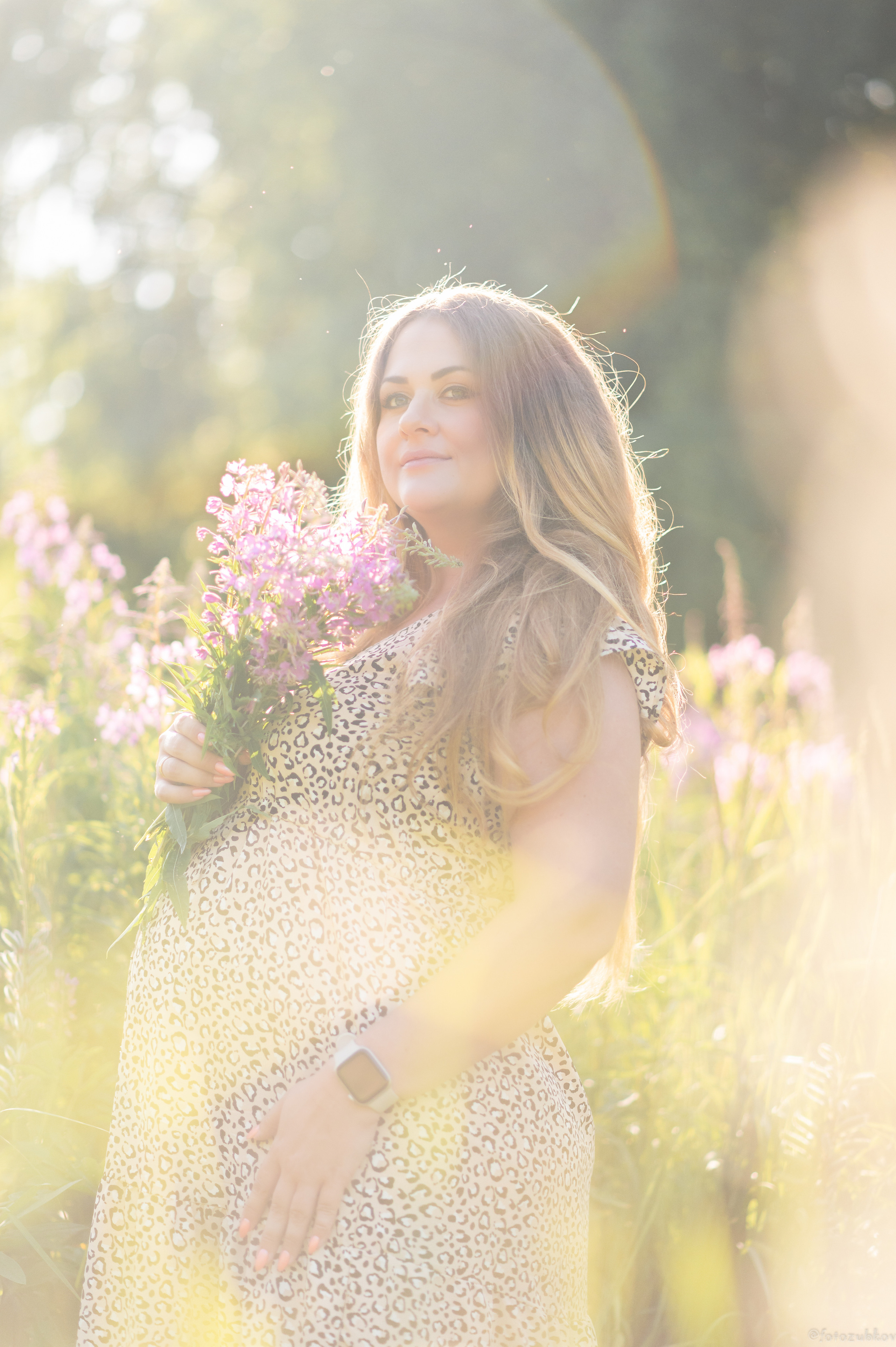 Беременная девушка с цветами в поле