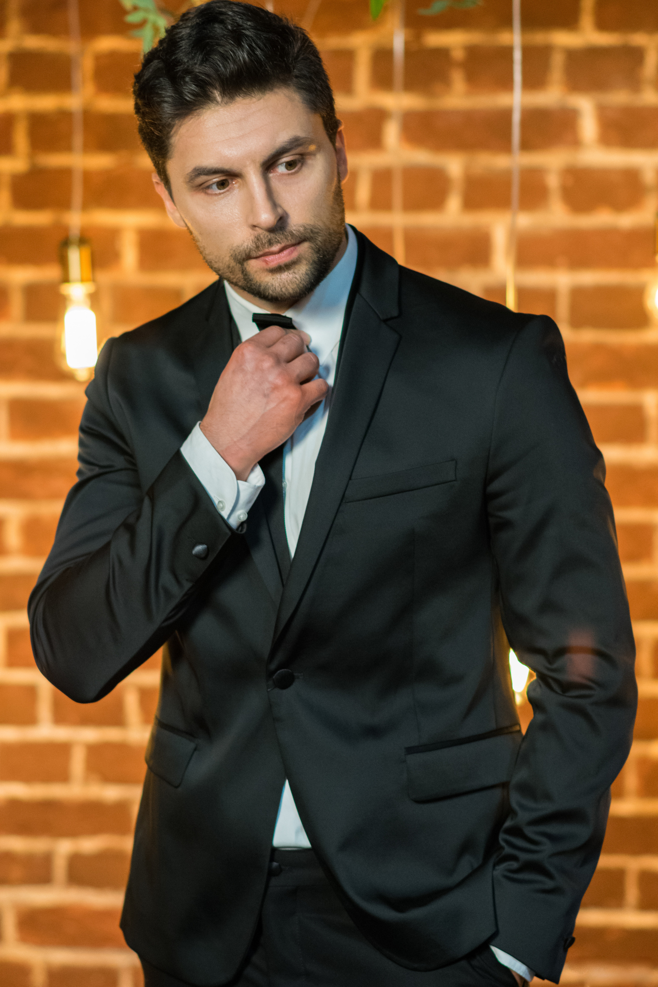 Мужчина в костюме на фоне кирпичной стены