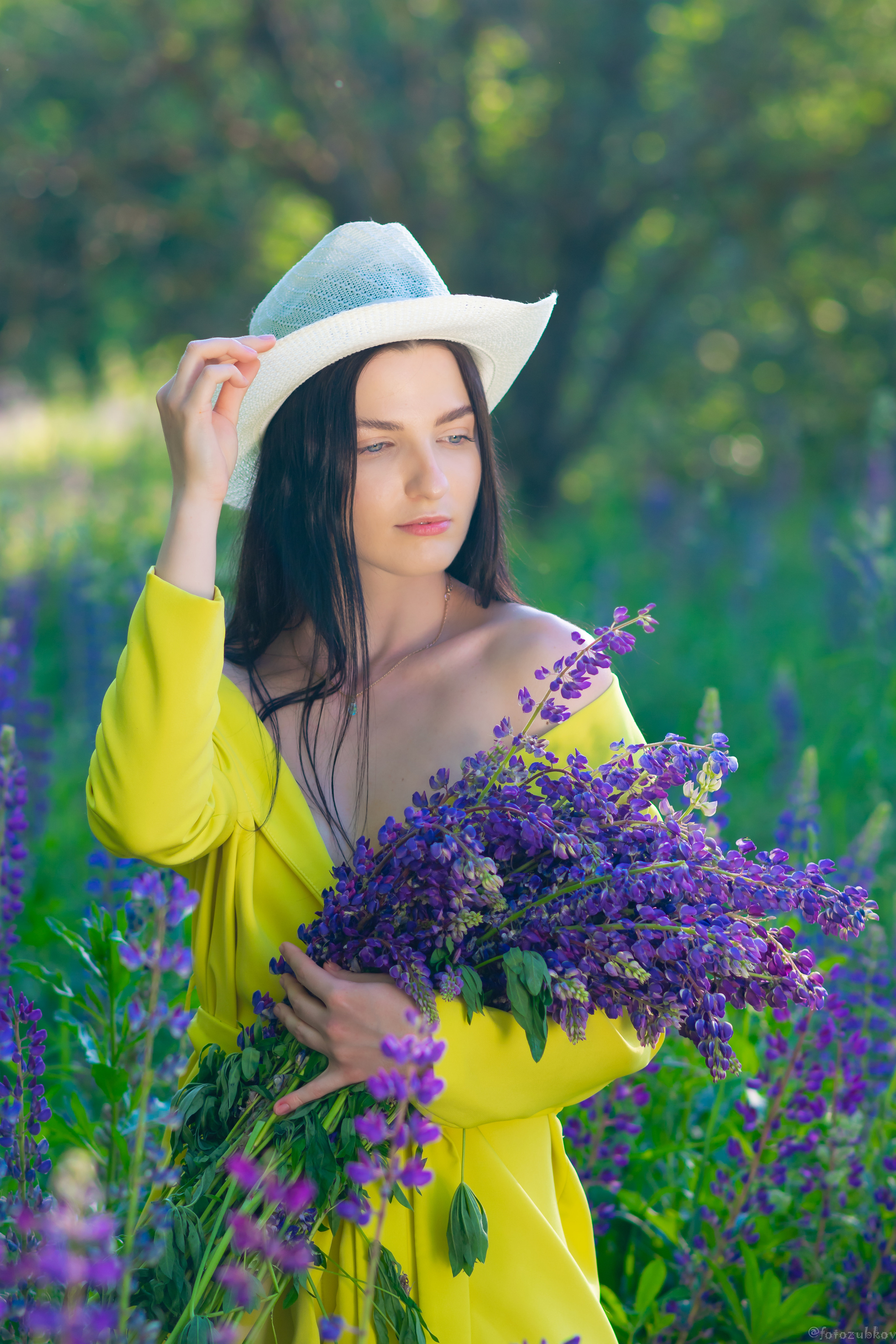 Девушка в жёлтом платье с букетом люпинов в парке