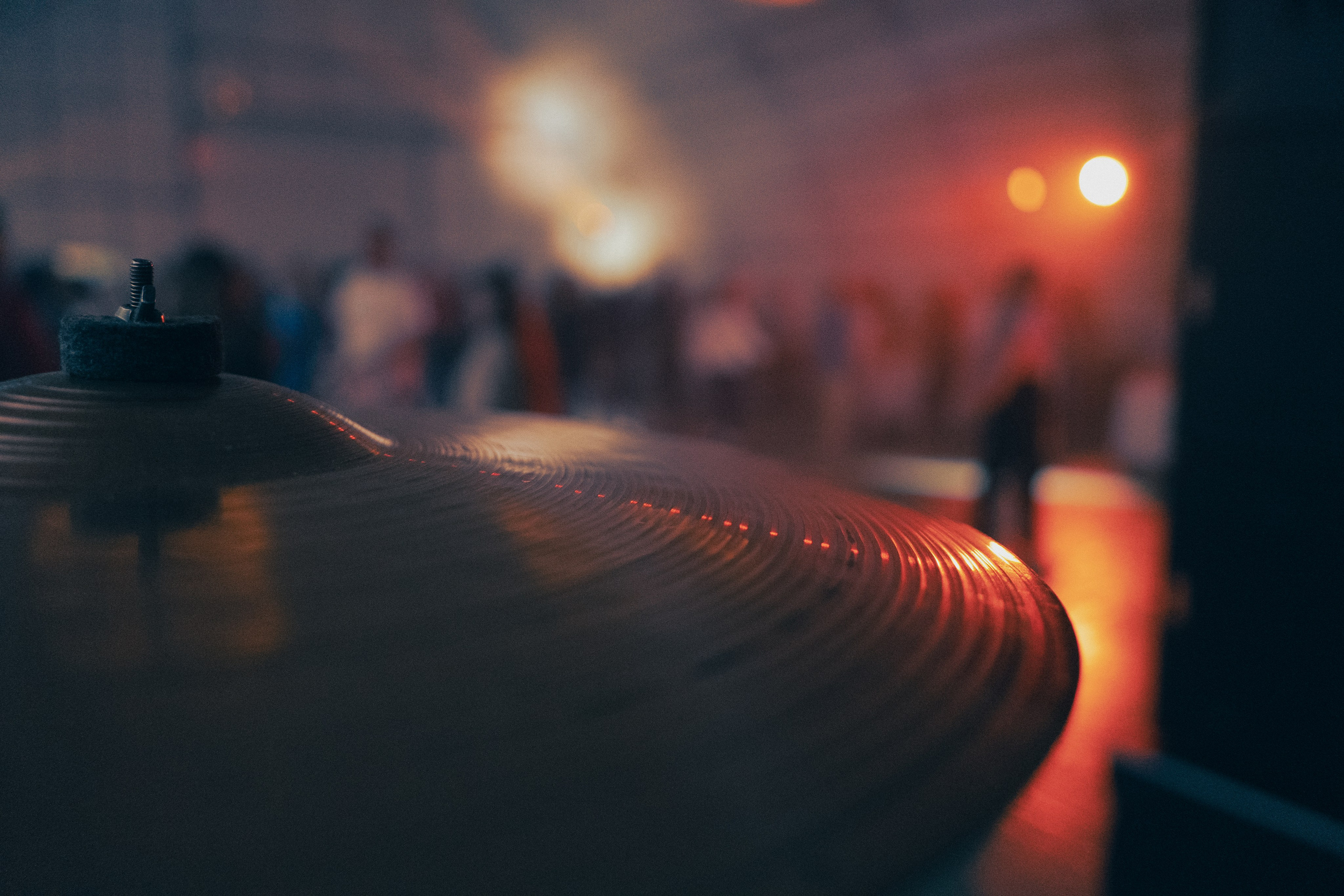 Крупный план тарелки ударной установки на концерте, размытый фон с огнями и людьми