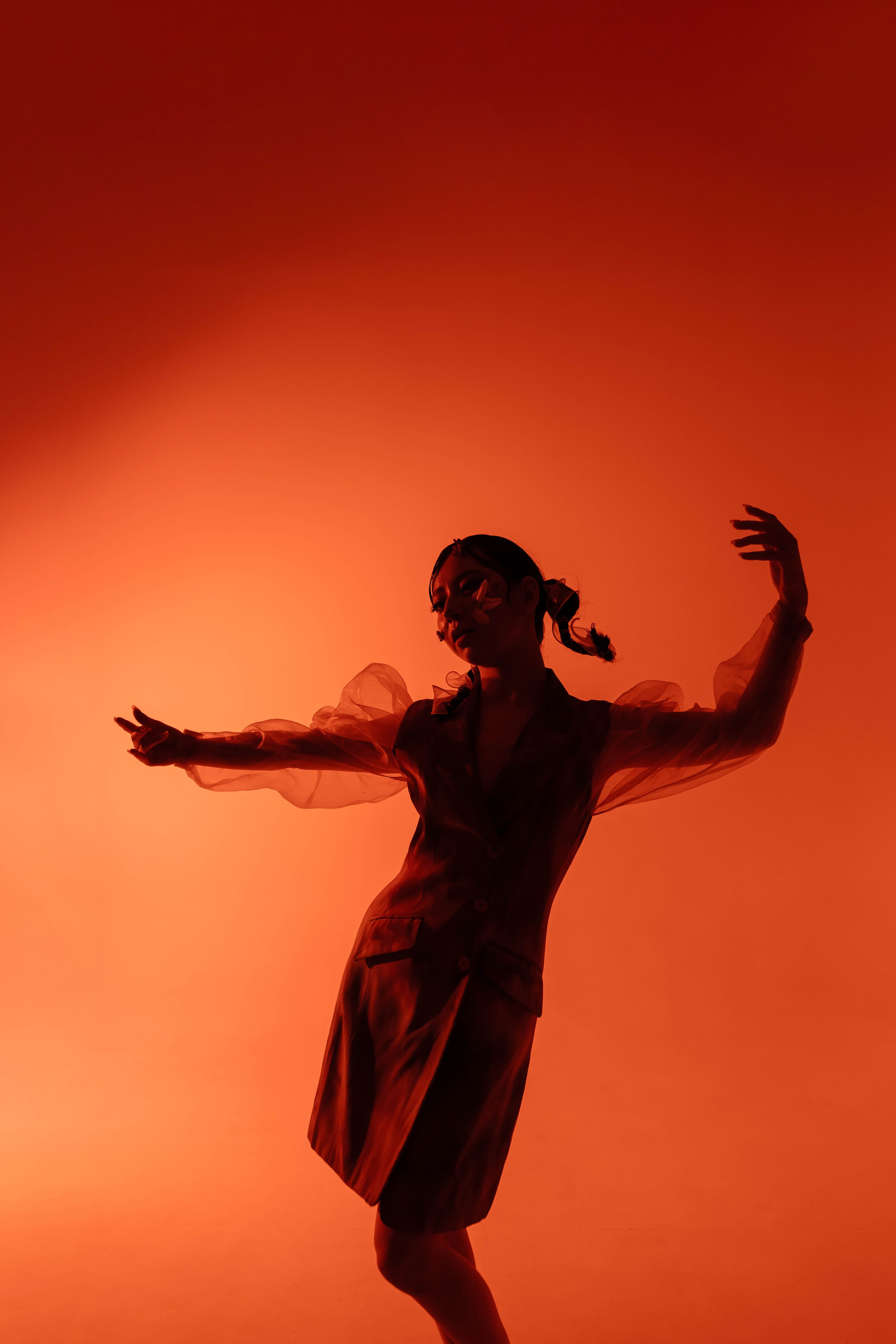 Модель очаровывает публику плавными движениями в стильном наряде на ярком оранжевом фоне, который усиливает энергичность выступления.