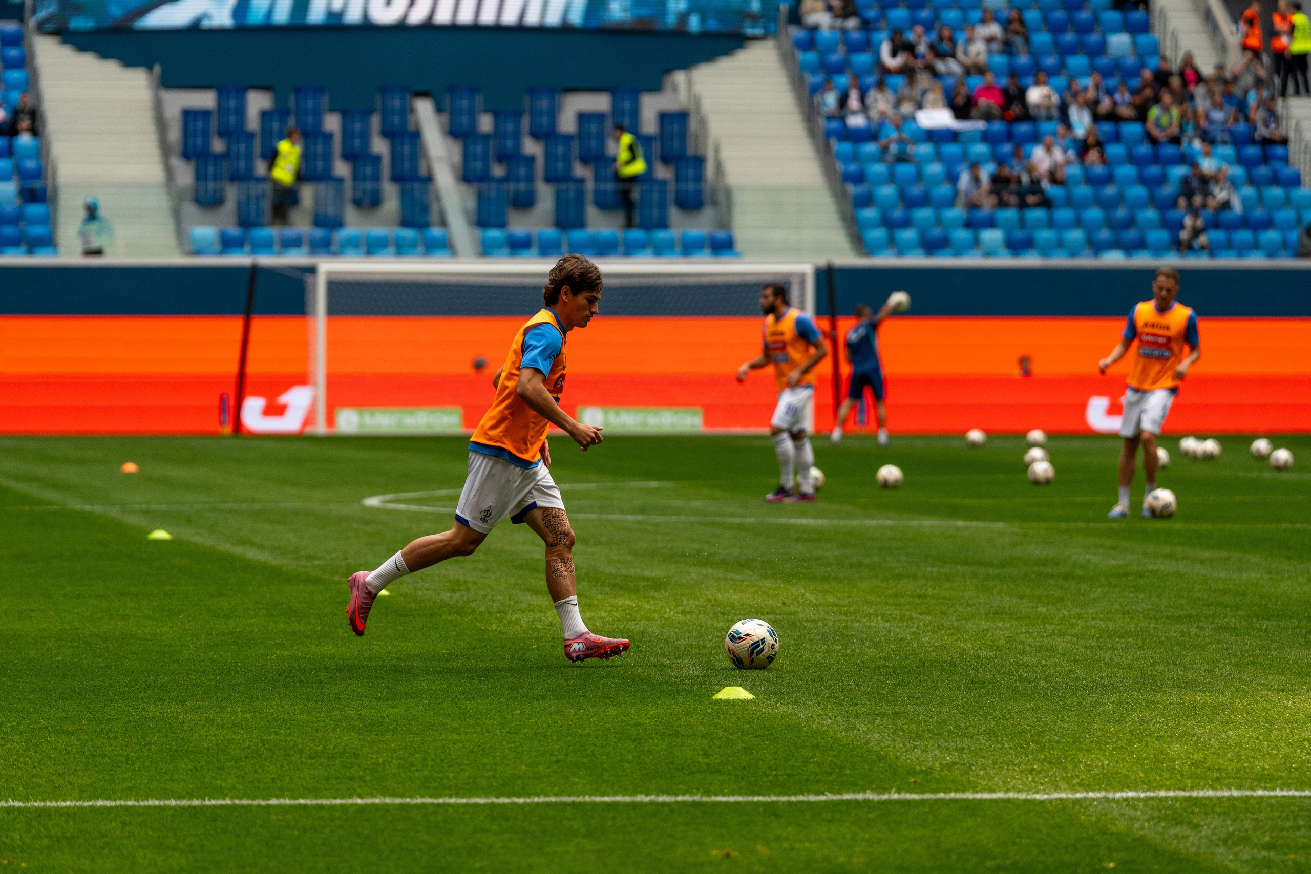 Футболист «Динамо» в оранжевой манишке ведёт мяч на Газпром Арене