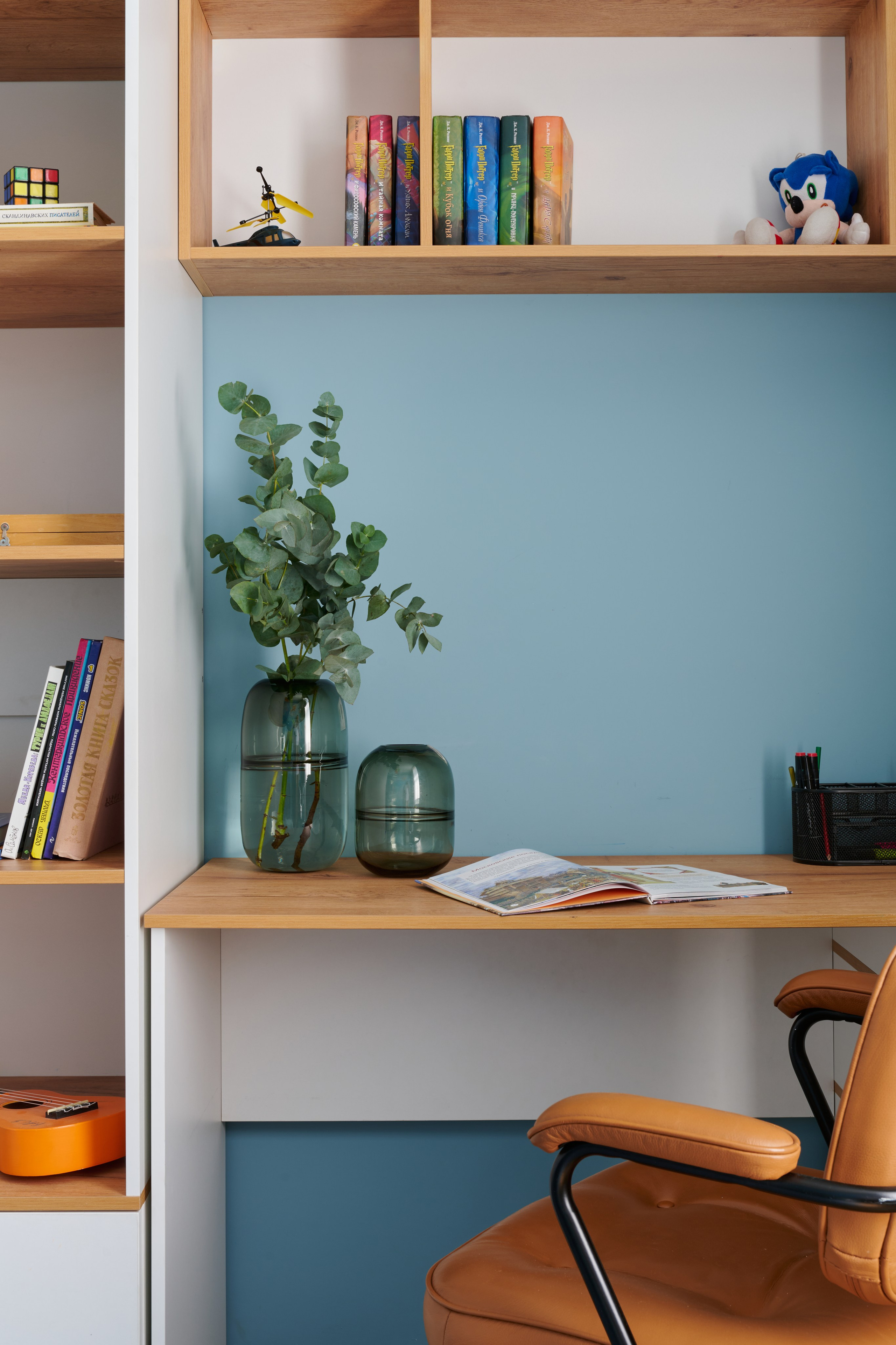 Рабочий стол у голубой стены, открытые полки, декор