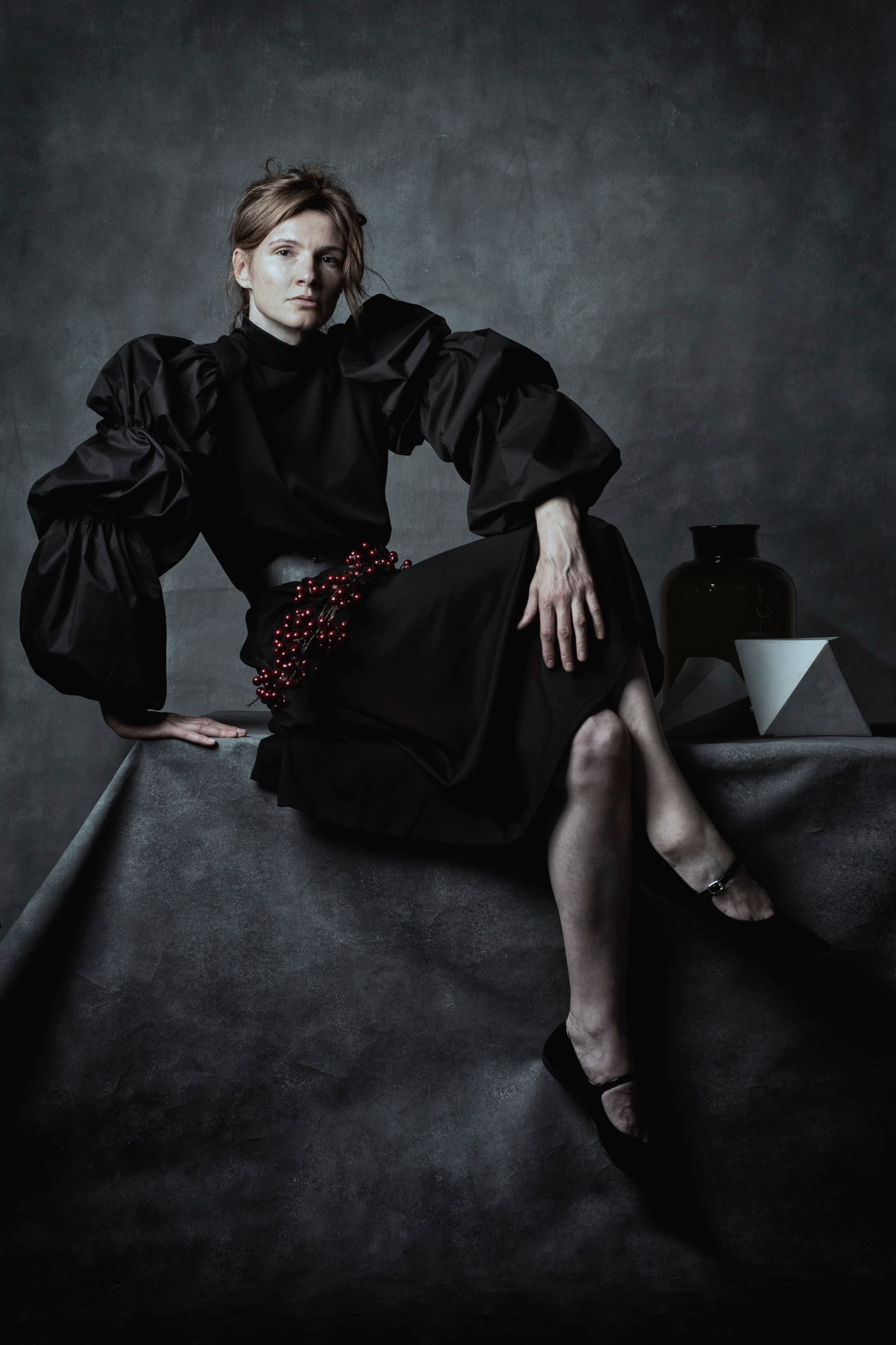 Девушка сидит на столе в необычном платье рядом с пирамидой 