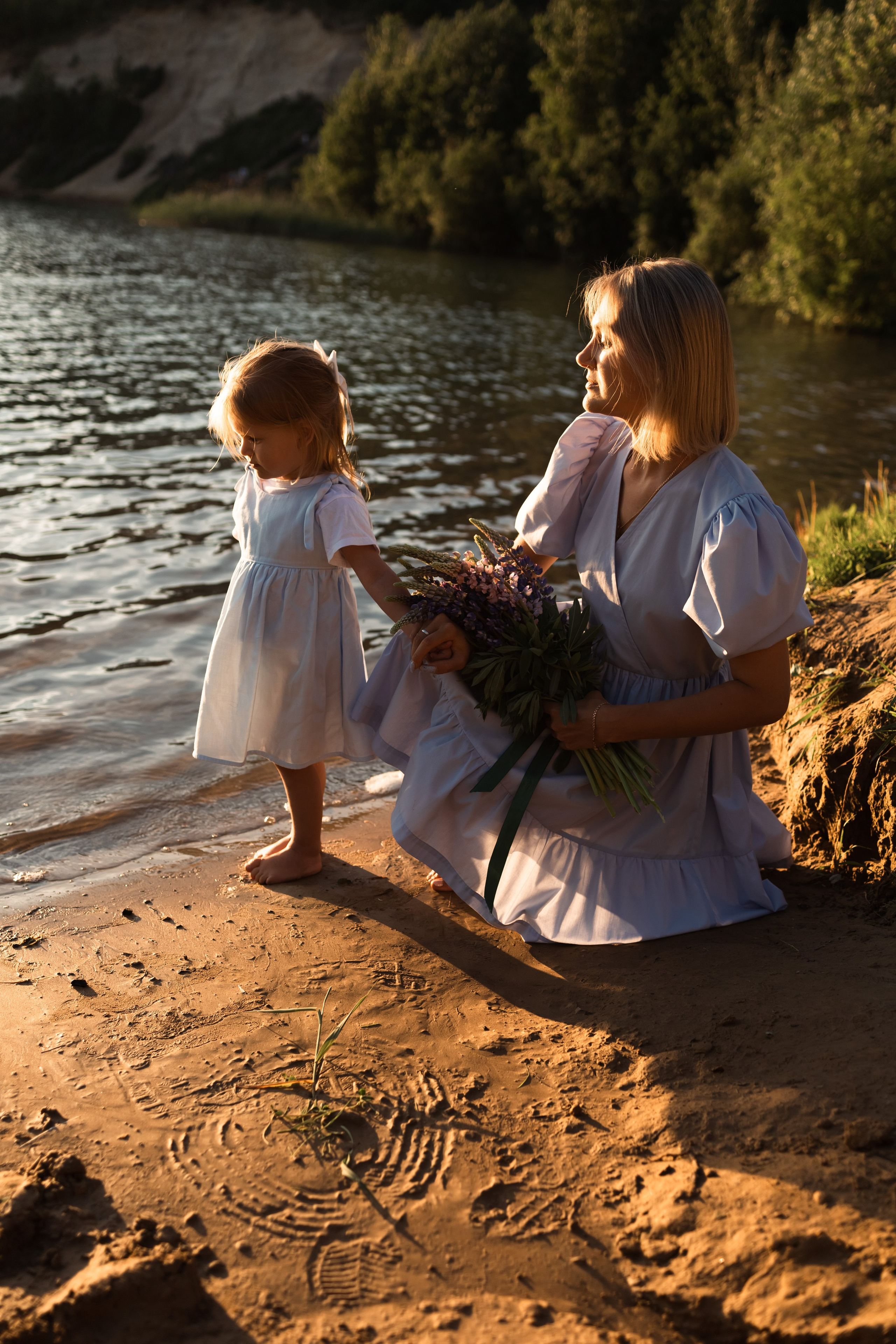 мама и дочка в красивом закатном свете у озера