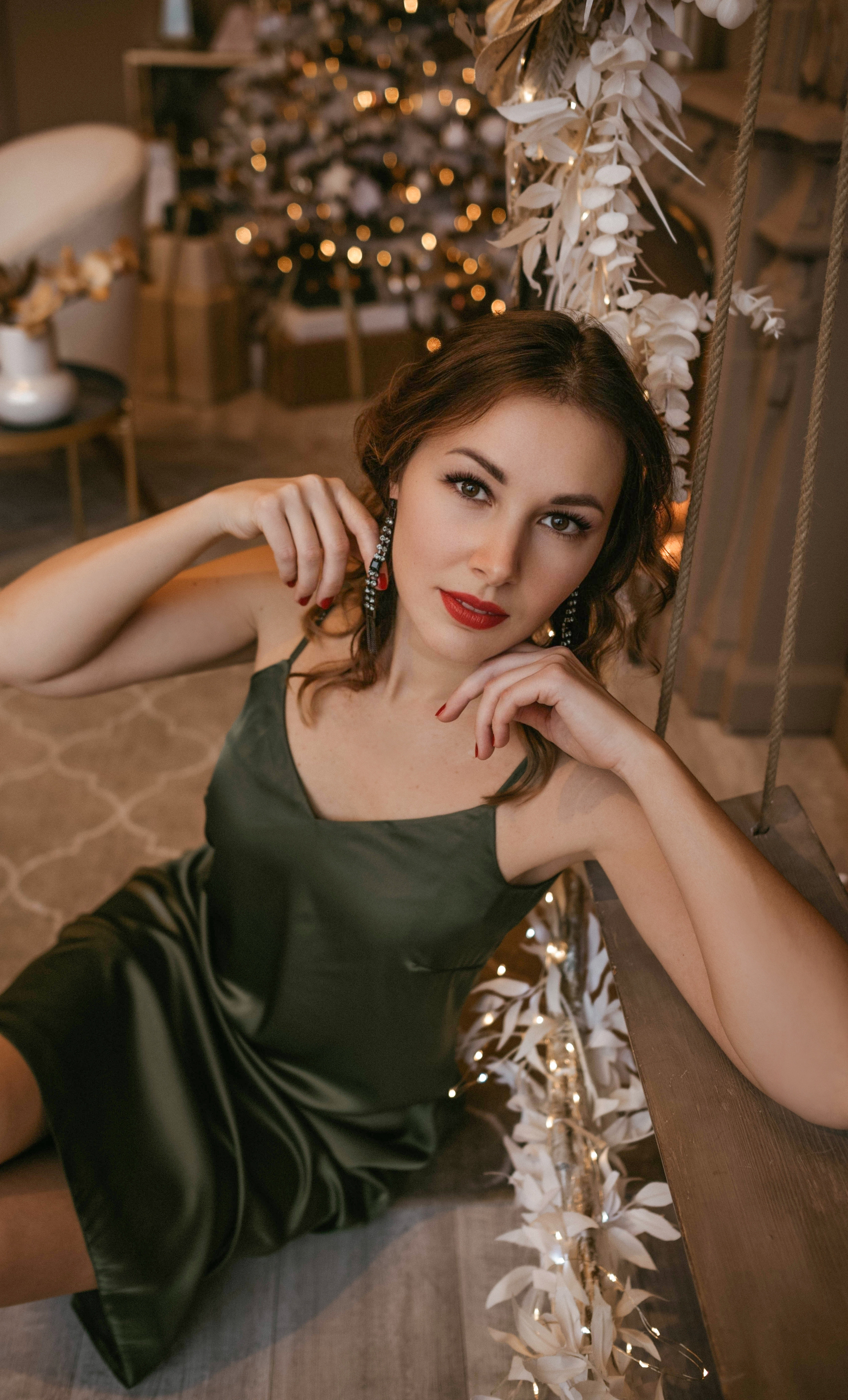Красивая девушка в зеленом платье позирует фотографу на Новый год