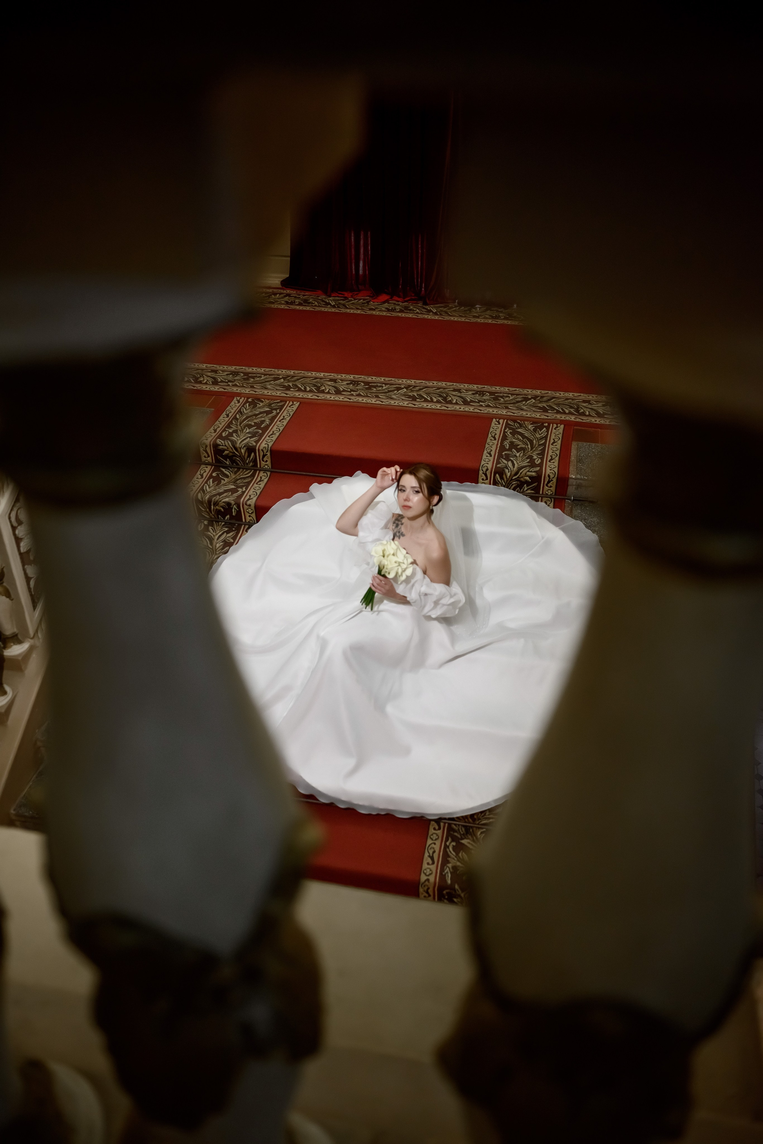 Невеста в белом платье сидин на ступенях большой лестницы