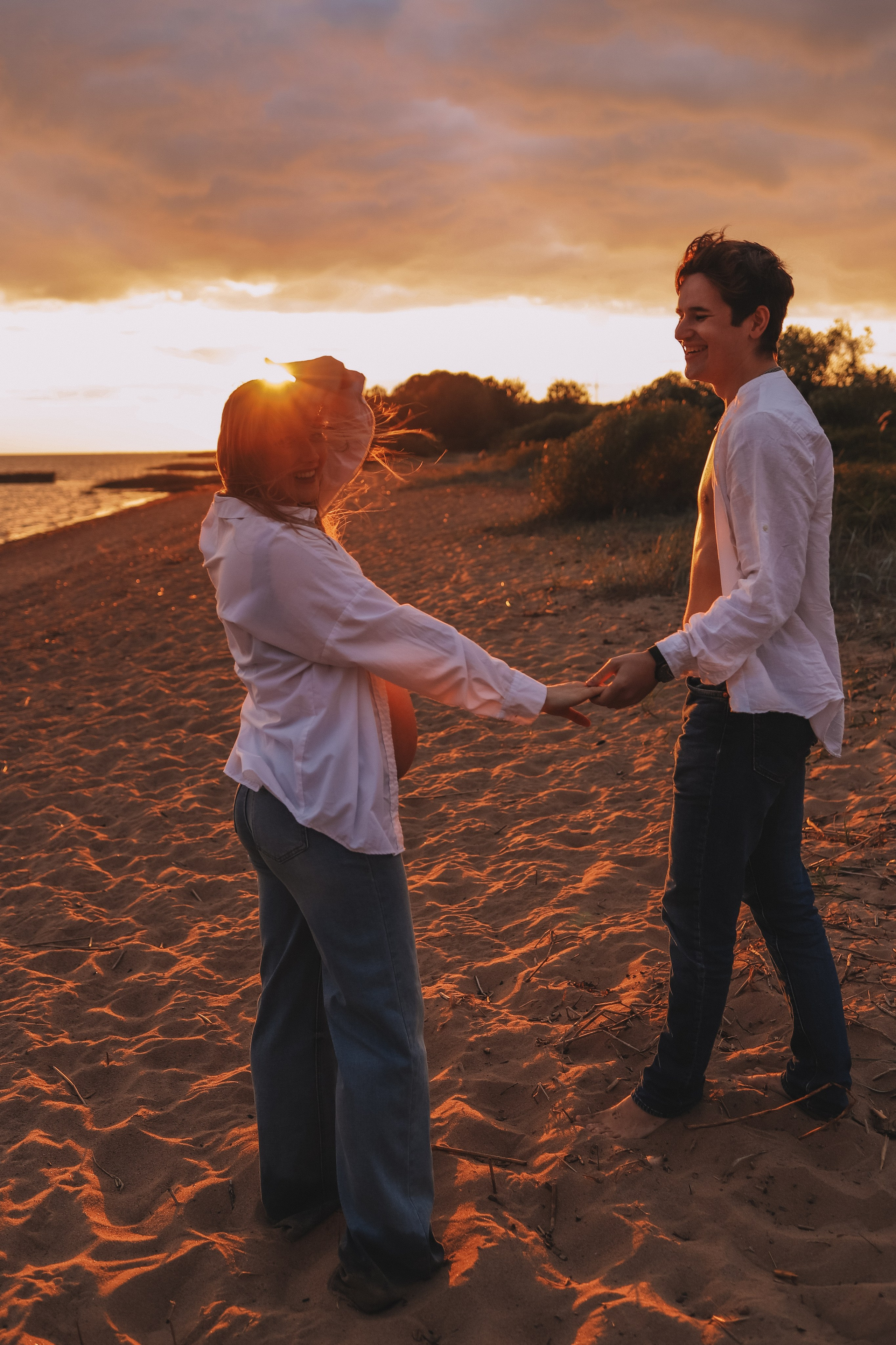 Пара идёт по песку, держась за руки, закатный свет