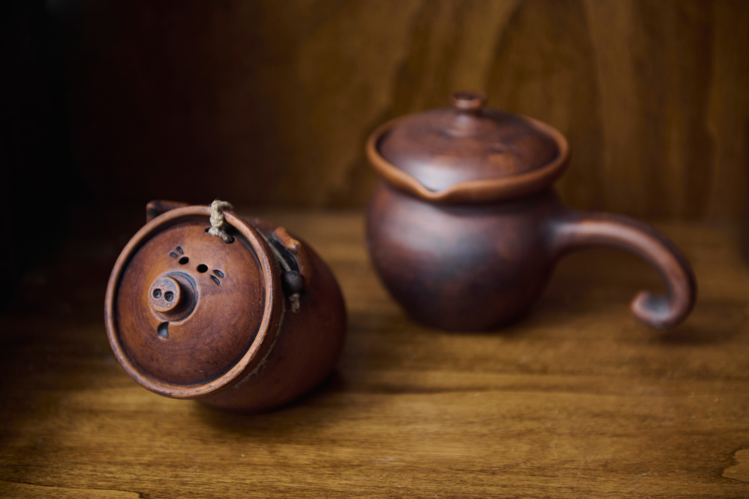 Глиняный чайник и чашка на деревянной столешнице / Керамический набор на столе, предметный акцент
