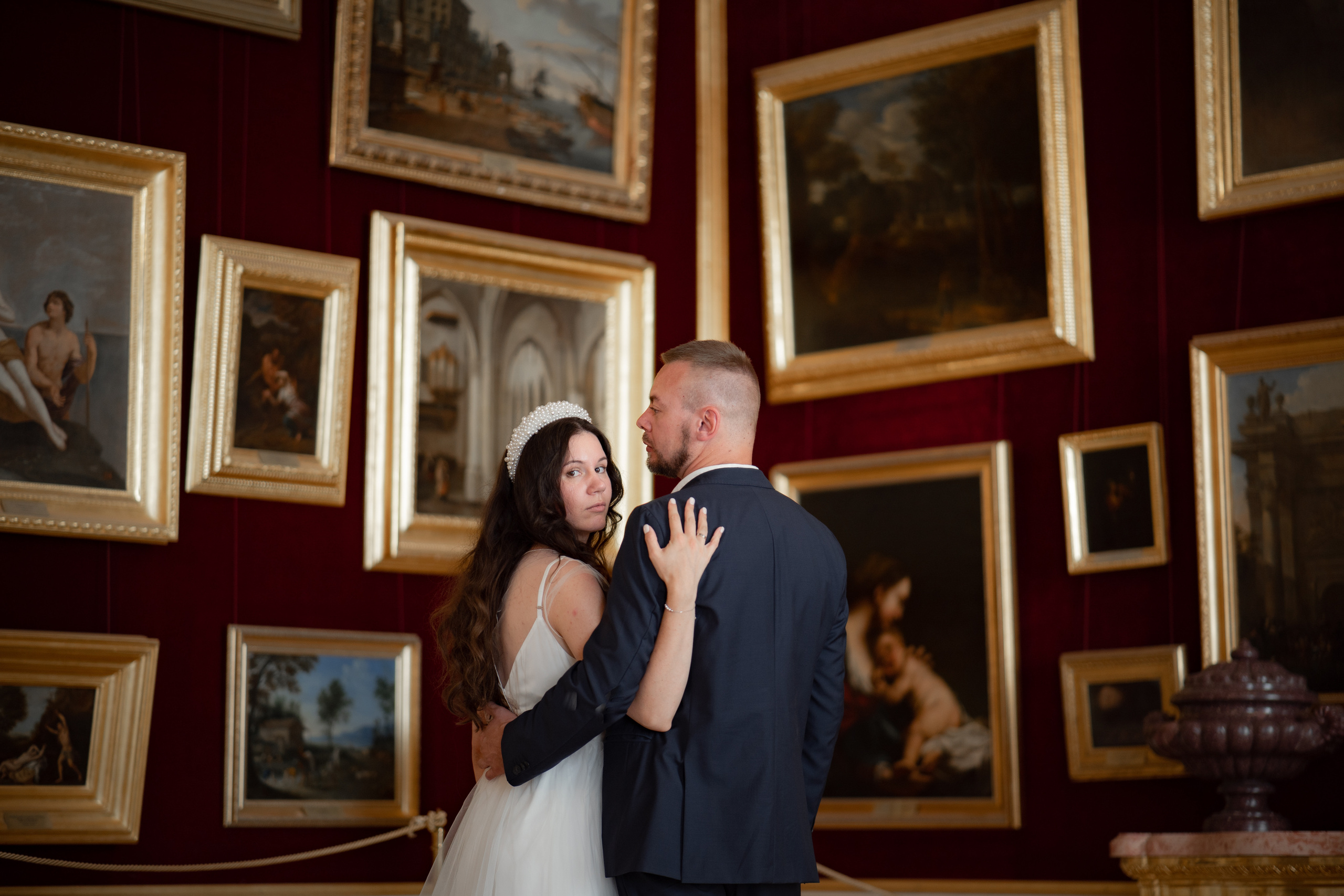 Жених и невеста фотографируются на фоне картин в Гатчинском дворце