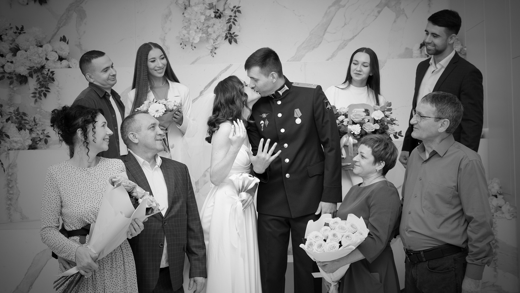 черно белое фото где жених с невестой целуются и рядом с ними стоят их родственники и друзья 