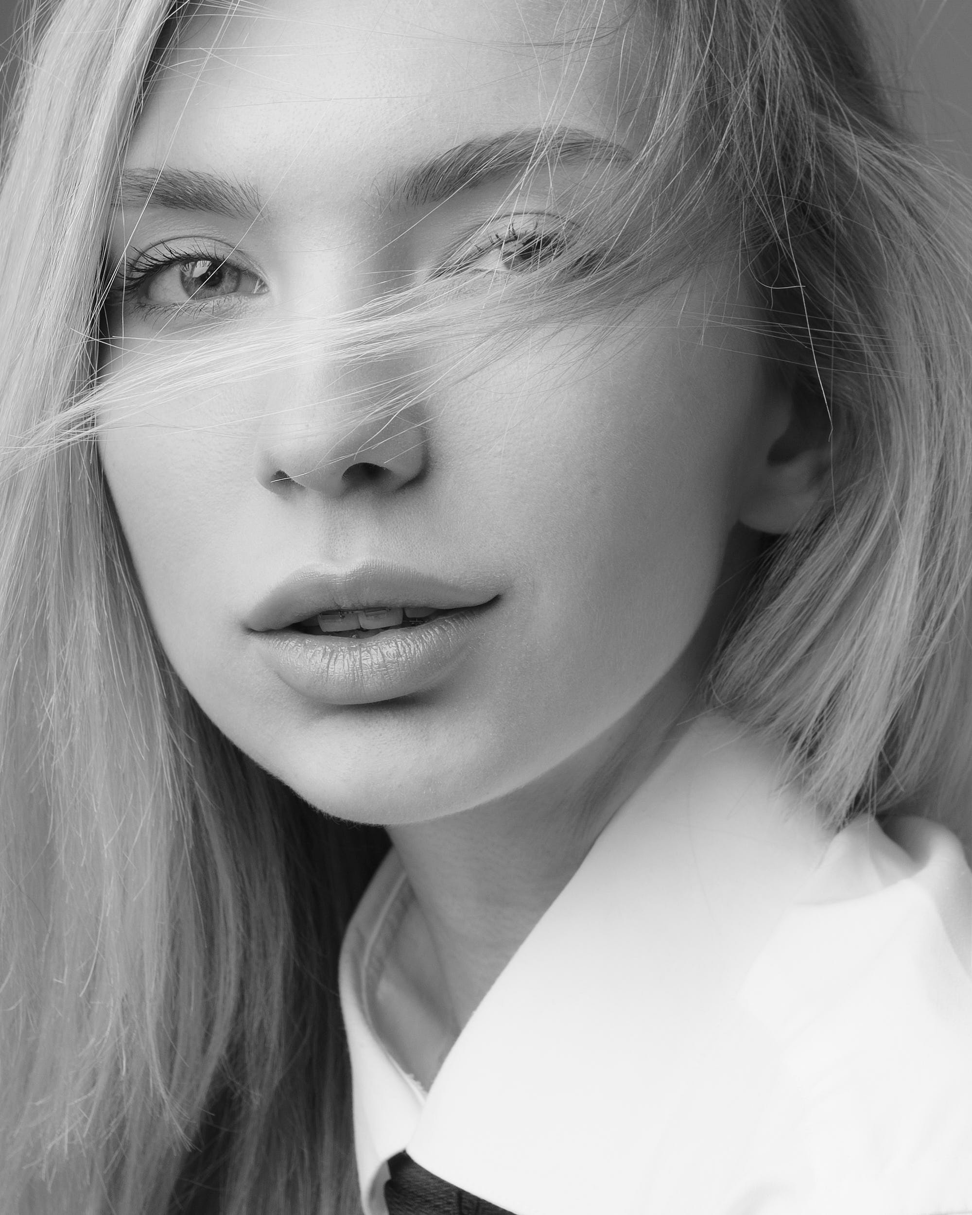 Черно белый крупный портрет девушки с развивающимися волосами смотрящей в кадр