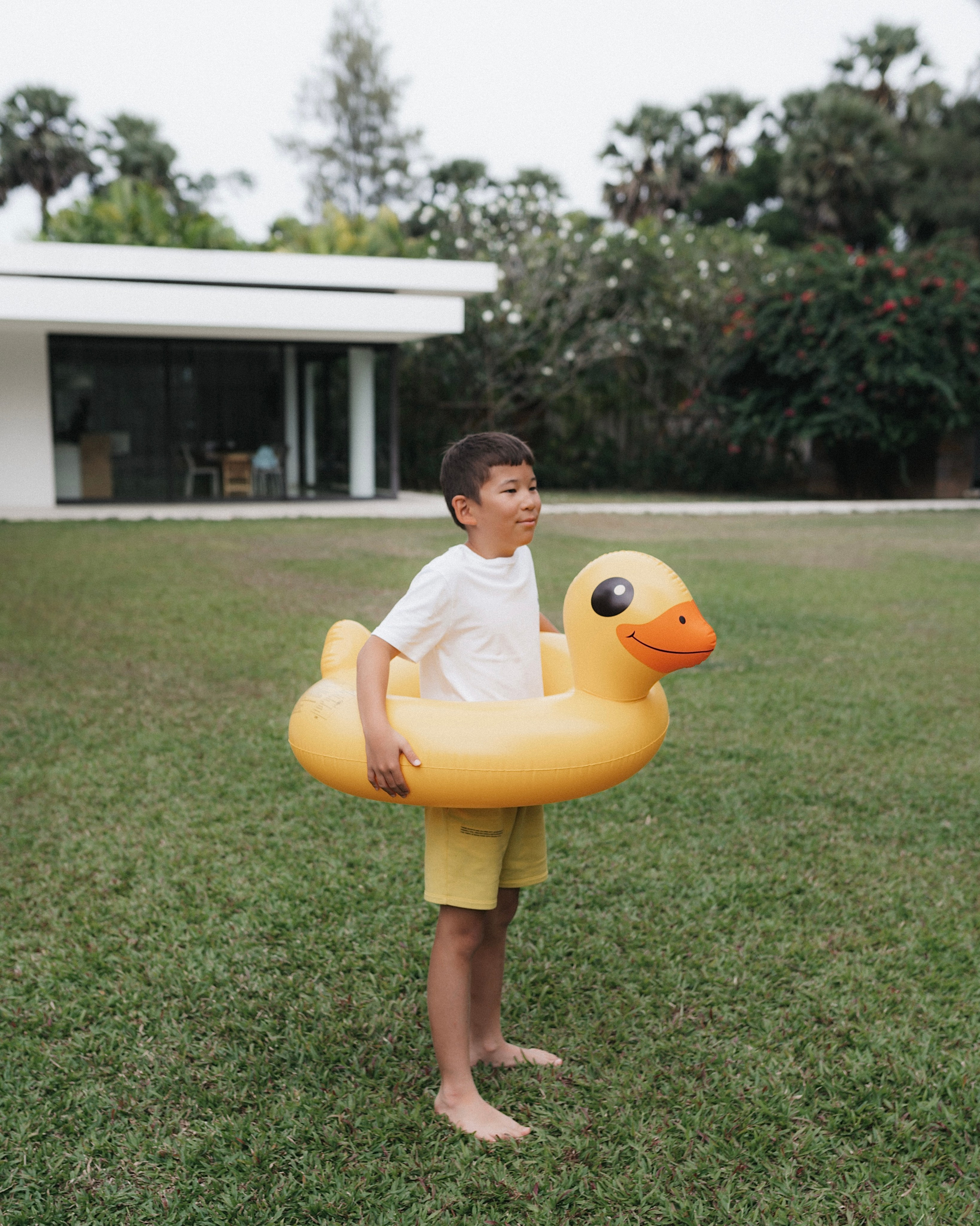 Ребёнком с надувным кругом-уткой на газоне, семейный кадр на вилле