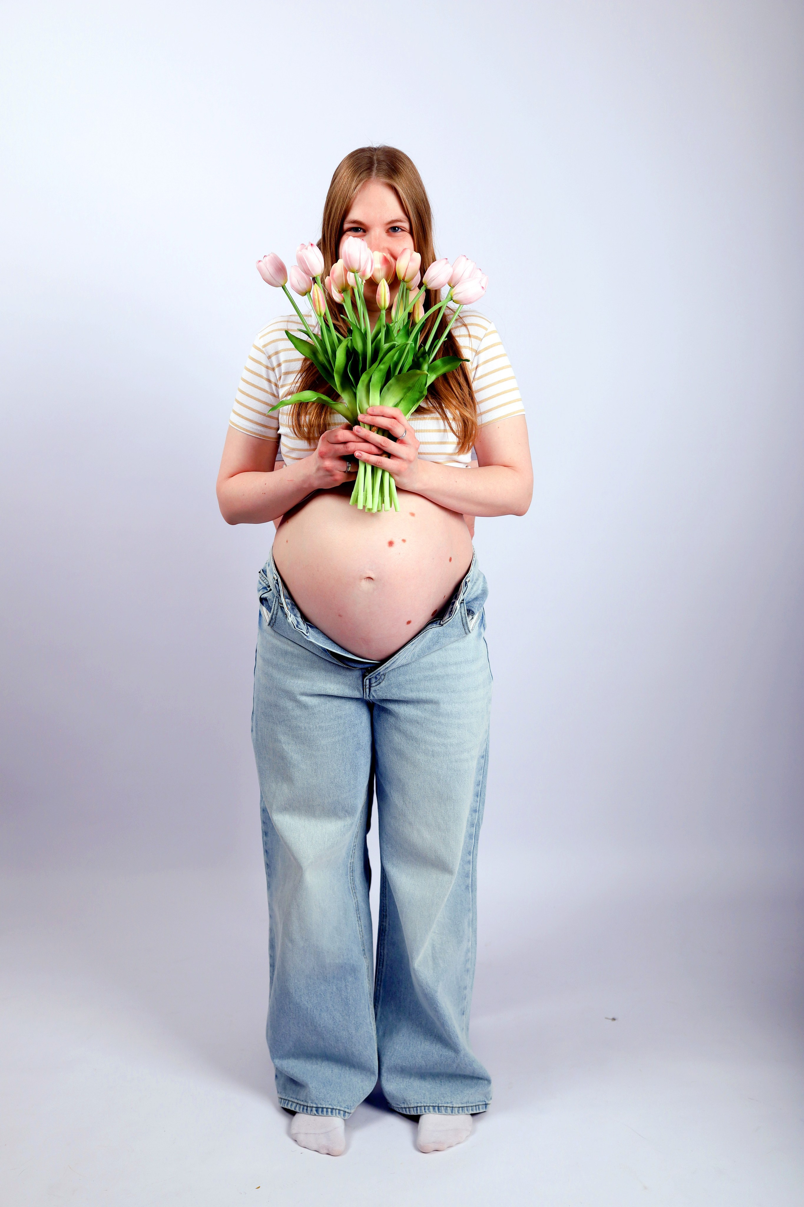 на фото беременная девушка с нежным букетом тюльпанов 