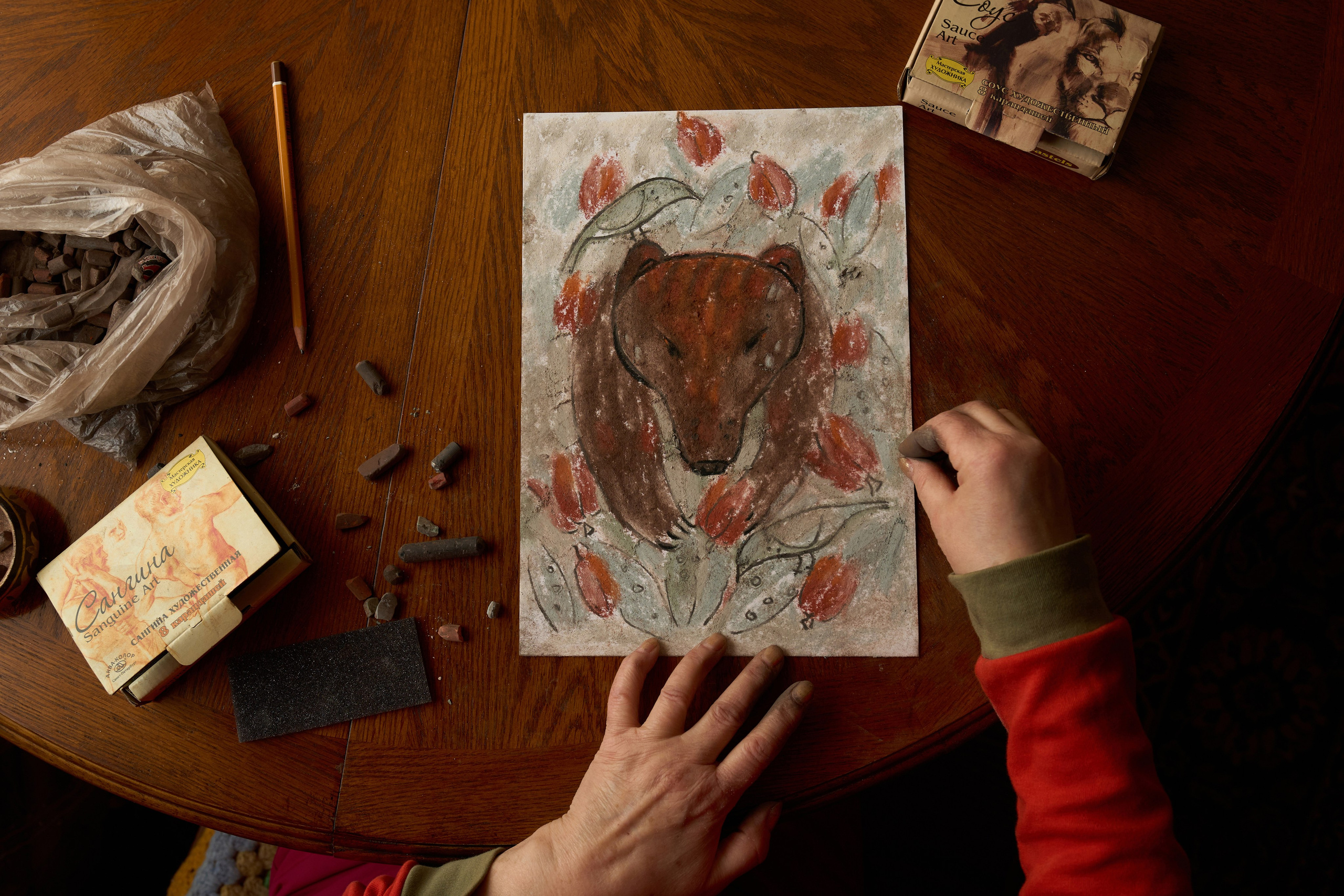 Lyubov Arbachakova is drawing a bear with birds in her house in Ust- Kabyrza on 08th of March 2025. Historically, the Shor people were divided into clan groups, each named after their place of residence or lineage. Every clan had its own totemic, sacred animal. Lyubov’s clan is Tayosh, whose totem animal is the bear.