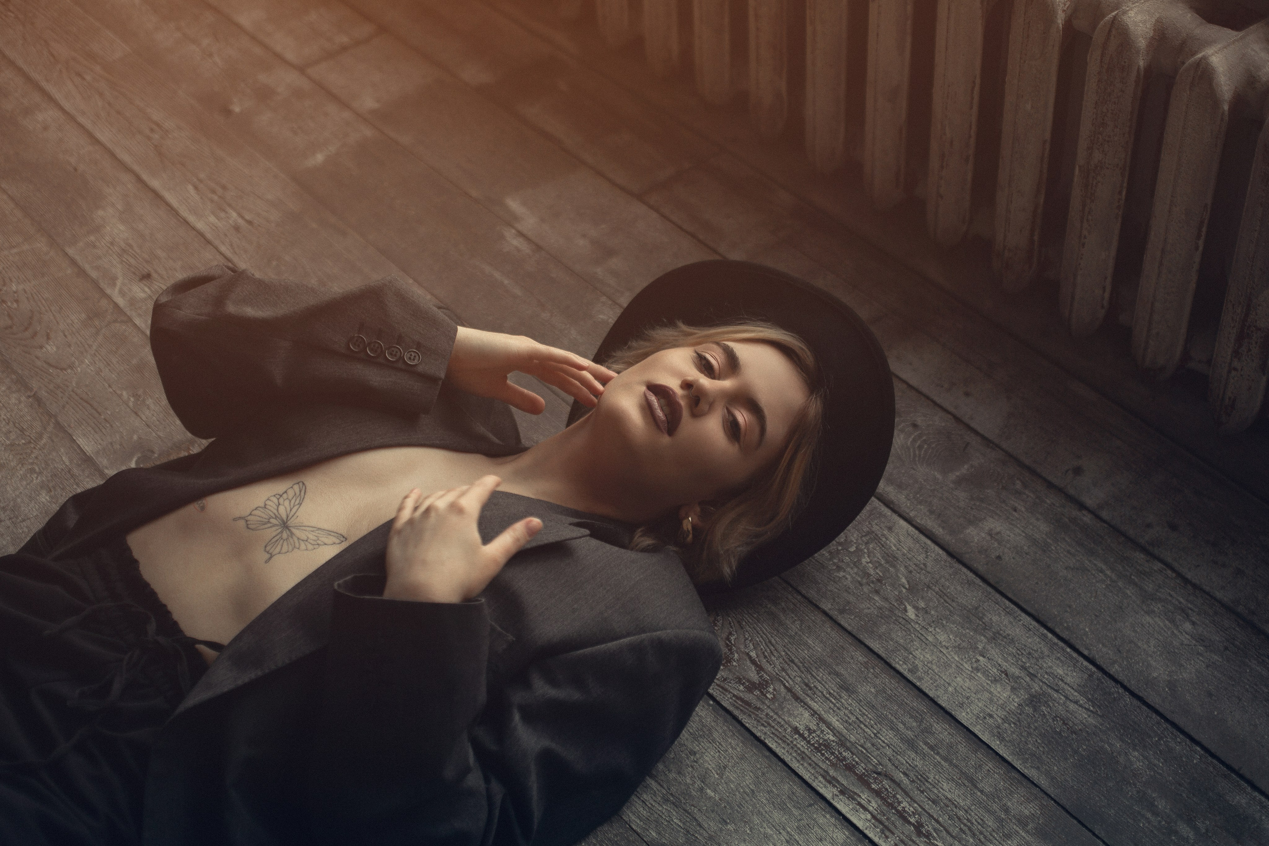 Драматичный портрет: девушка в шляпе на деревянном полу.