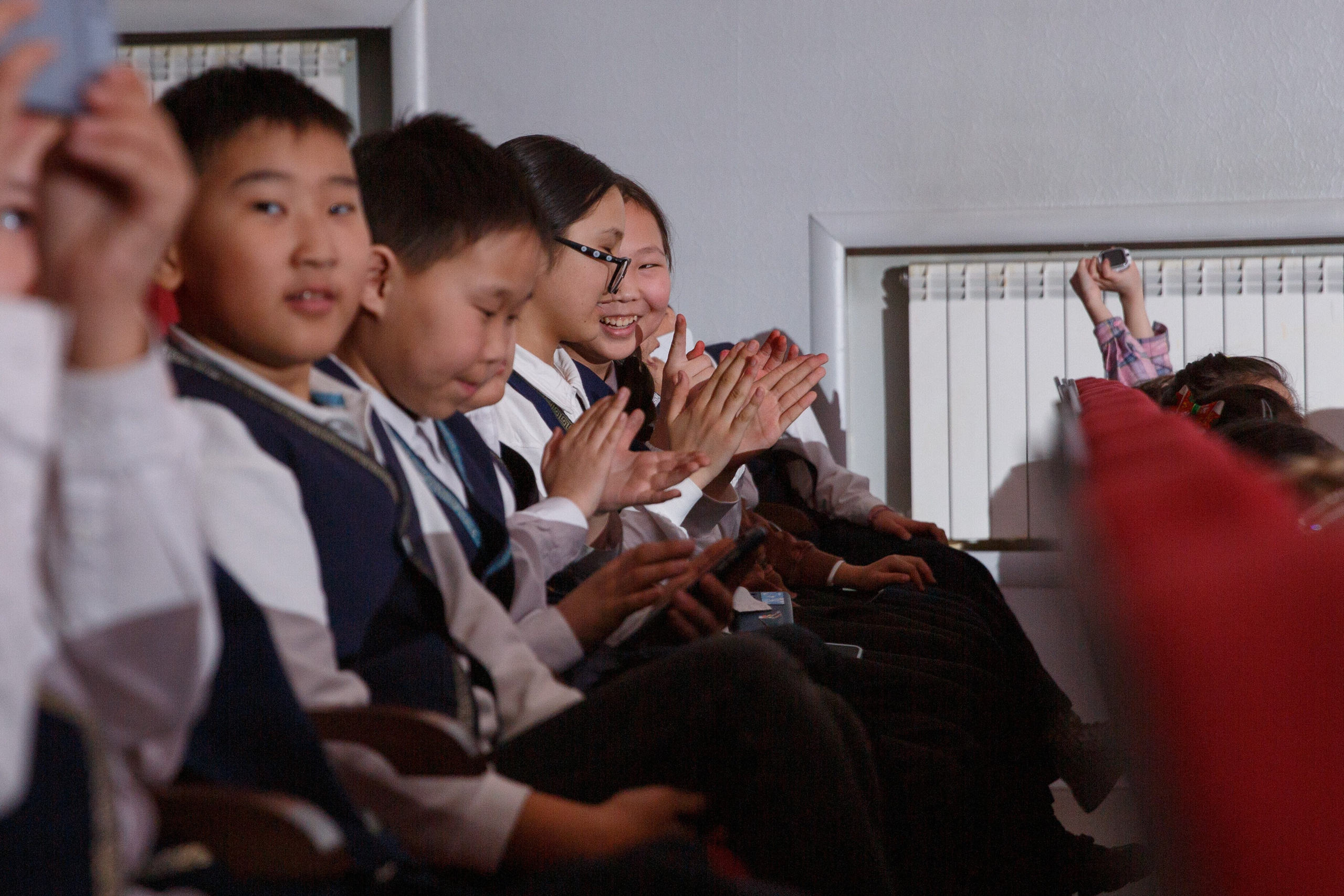 Школьники в зале аплодируют, радость и поддержка.