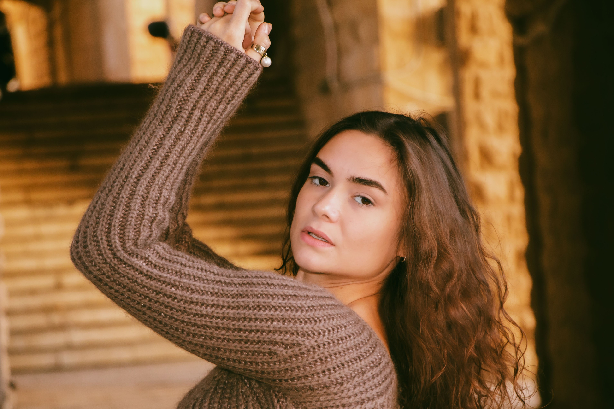 девушка стоит боком поняв руки в верх