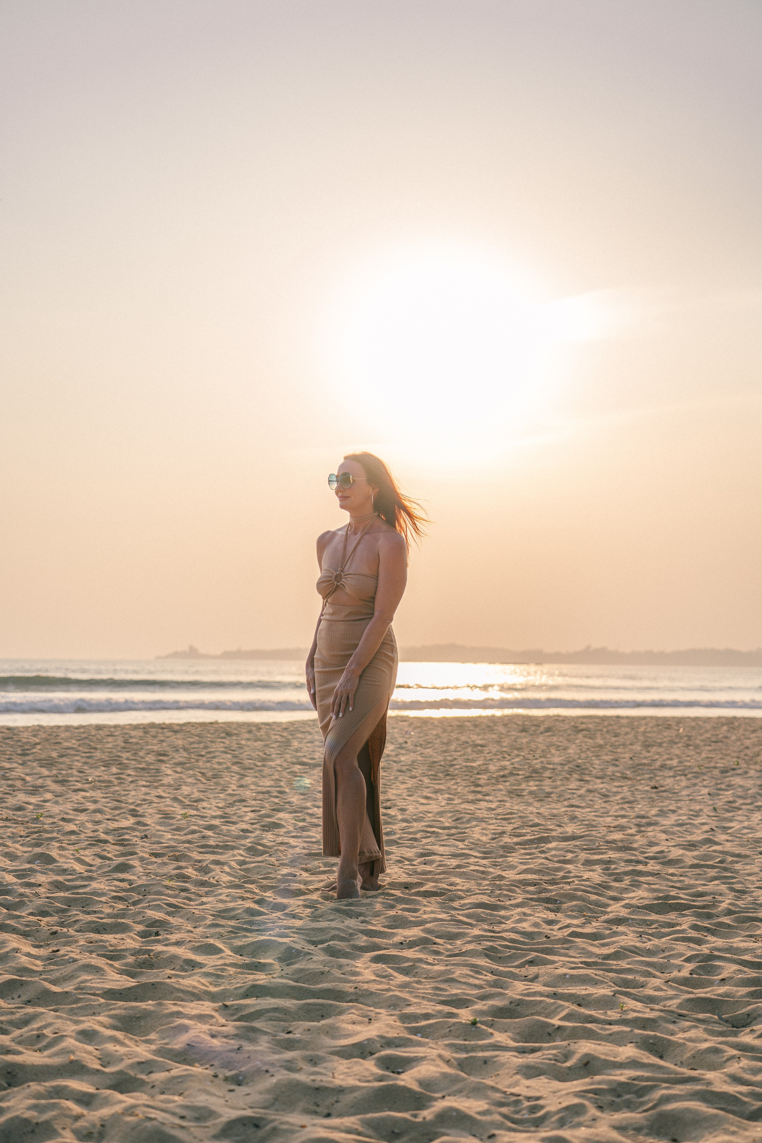 a girl in glasses on the beach under the bright sun