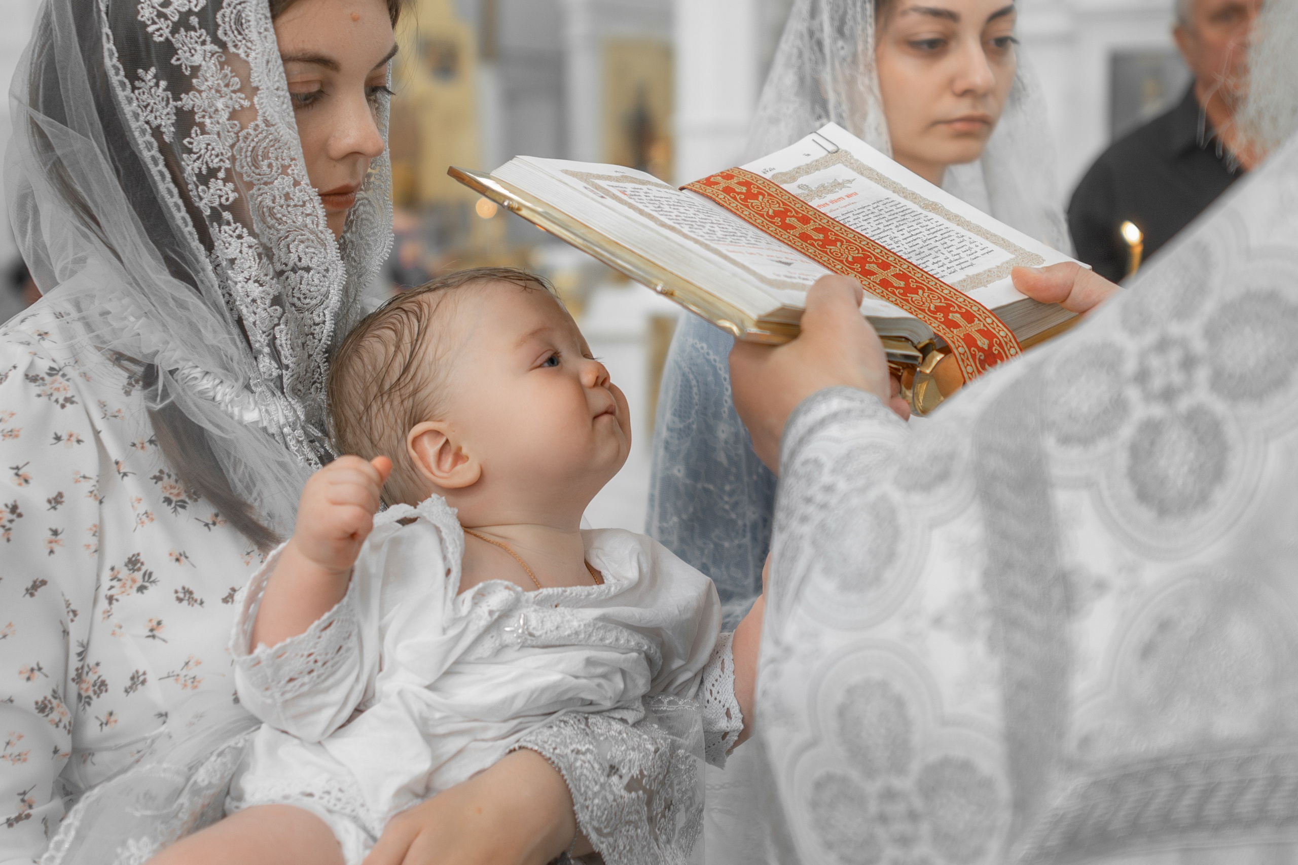 священник читает Евангелие над головой малыша