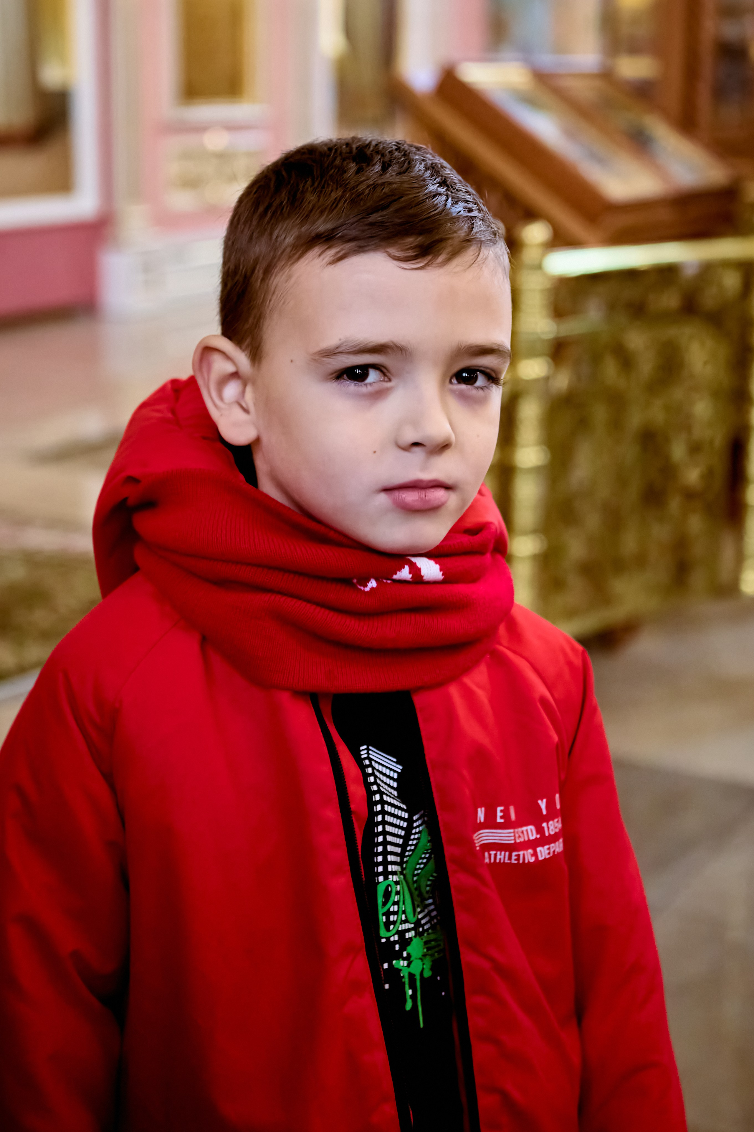 Мальчик 8-9 лет в красной куртке после Литургии в Храме