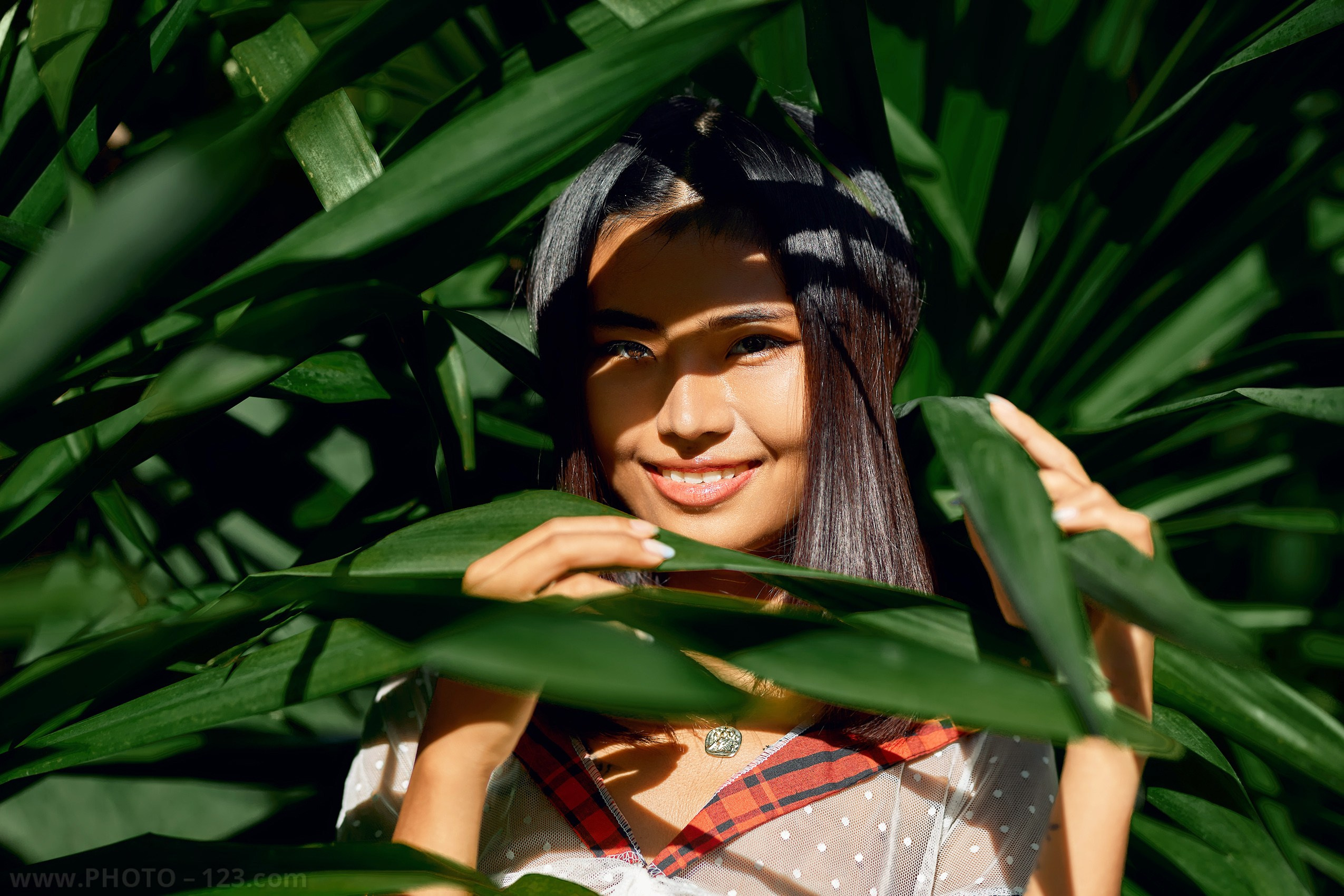 Portrait of a woman framed by tropical green leaves, natural light outdoor photoshoot by a professional photographer in Phu Quoc, Vietnam