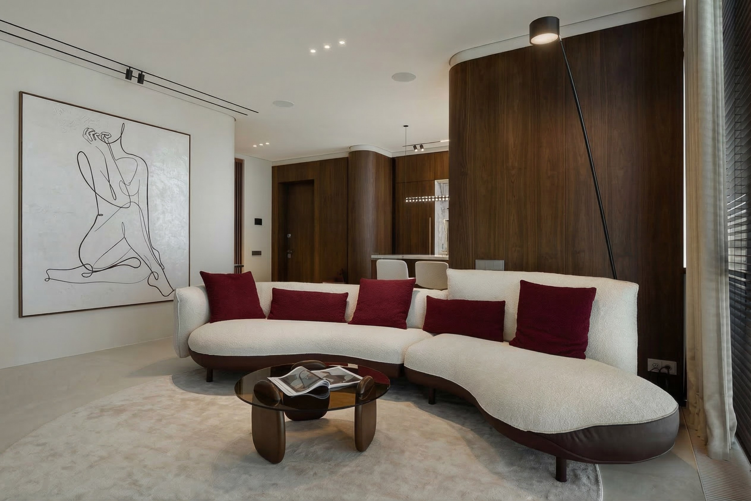 Интерьер гостиной в ЖК ONYX Deluxe: белый полукруглый диван с бордовыми подушками, кофейный столик из темного стекла и стеновые панели из дерева. Дизайн Валерии Котович.