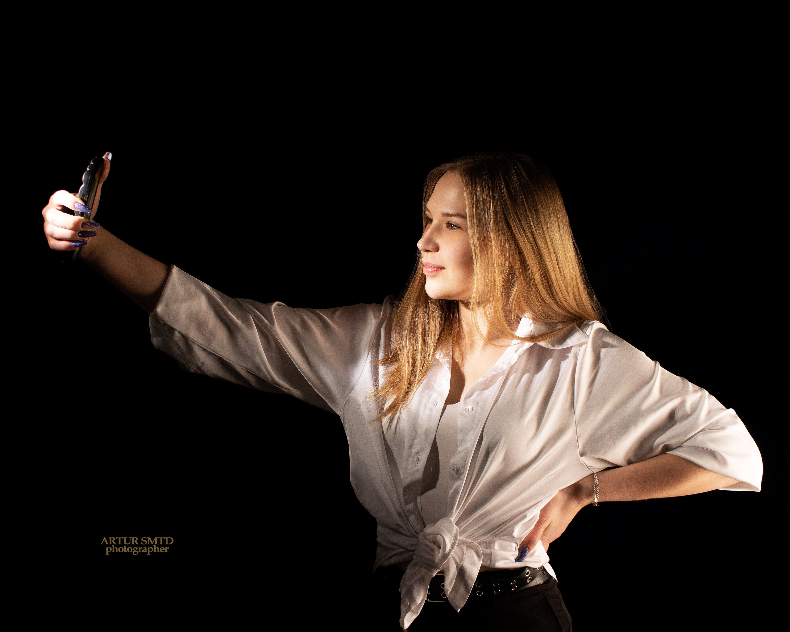 Девушка фотографирует себя на телефон во время фотосессии 